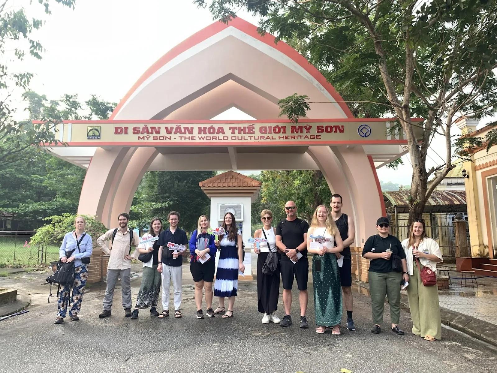 Fingo tour group posing at the My Son Sanctuary entrance gate under the UNESCO World Heritage sign before the private tour starts.