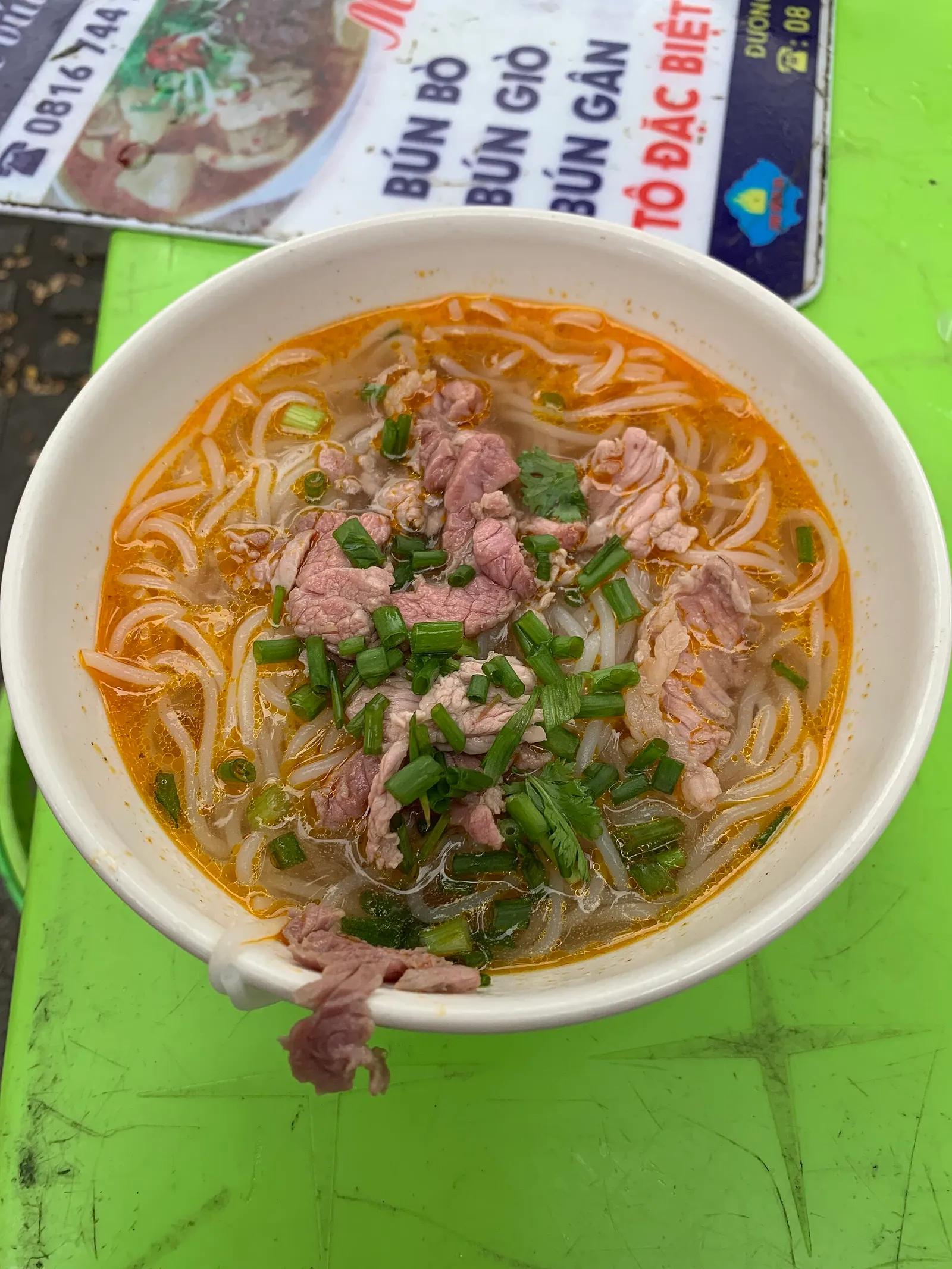 A bowl of bun bo Hue with sliced beef and spring onion at Dong Ba market.