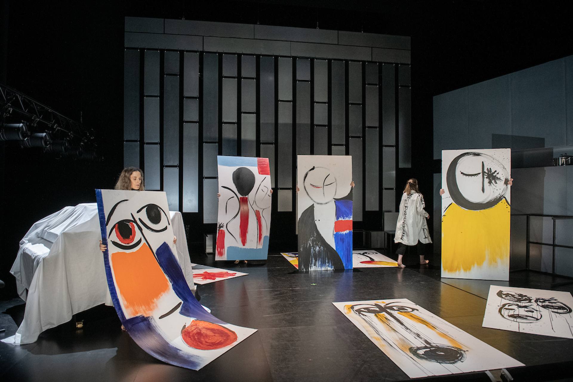 performers holding paintings on stage