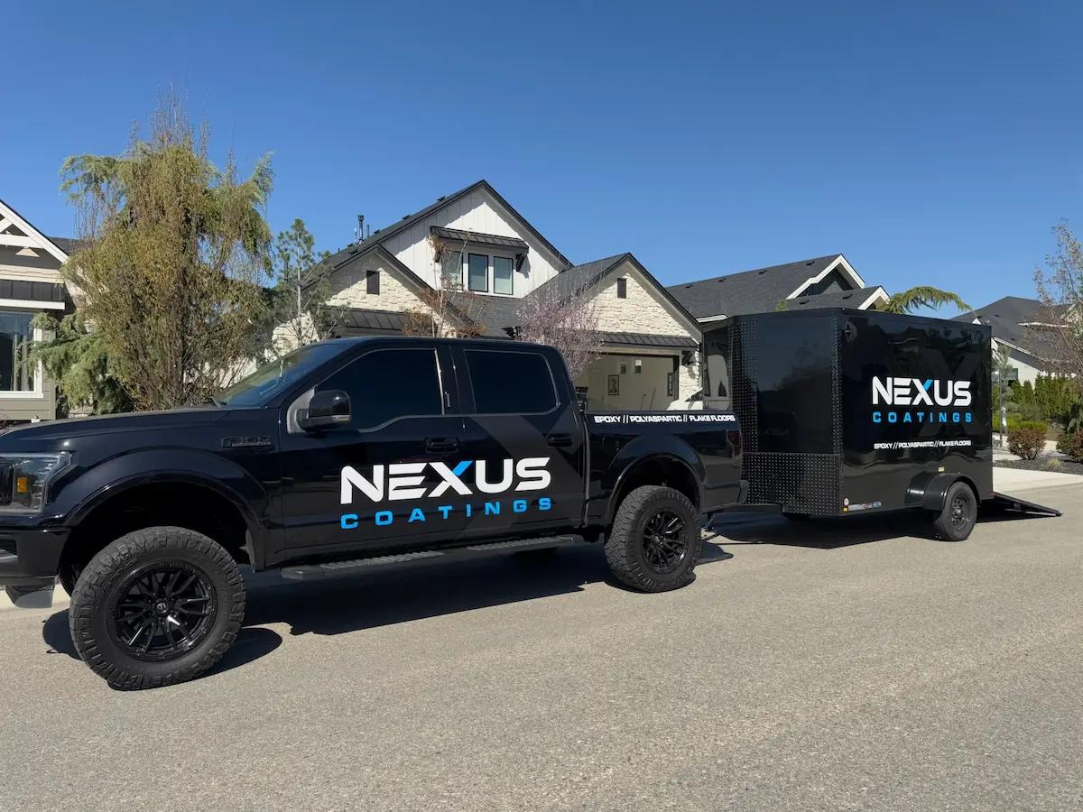 A black truck and trailer with the Nexus Coatings logo on them parked in front of a suburban home