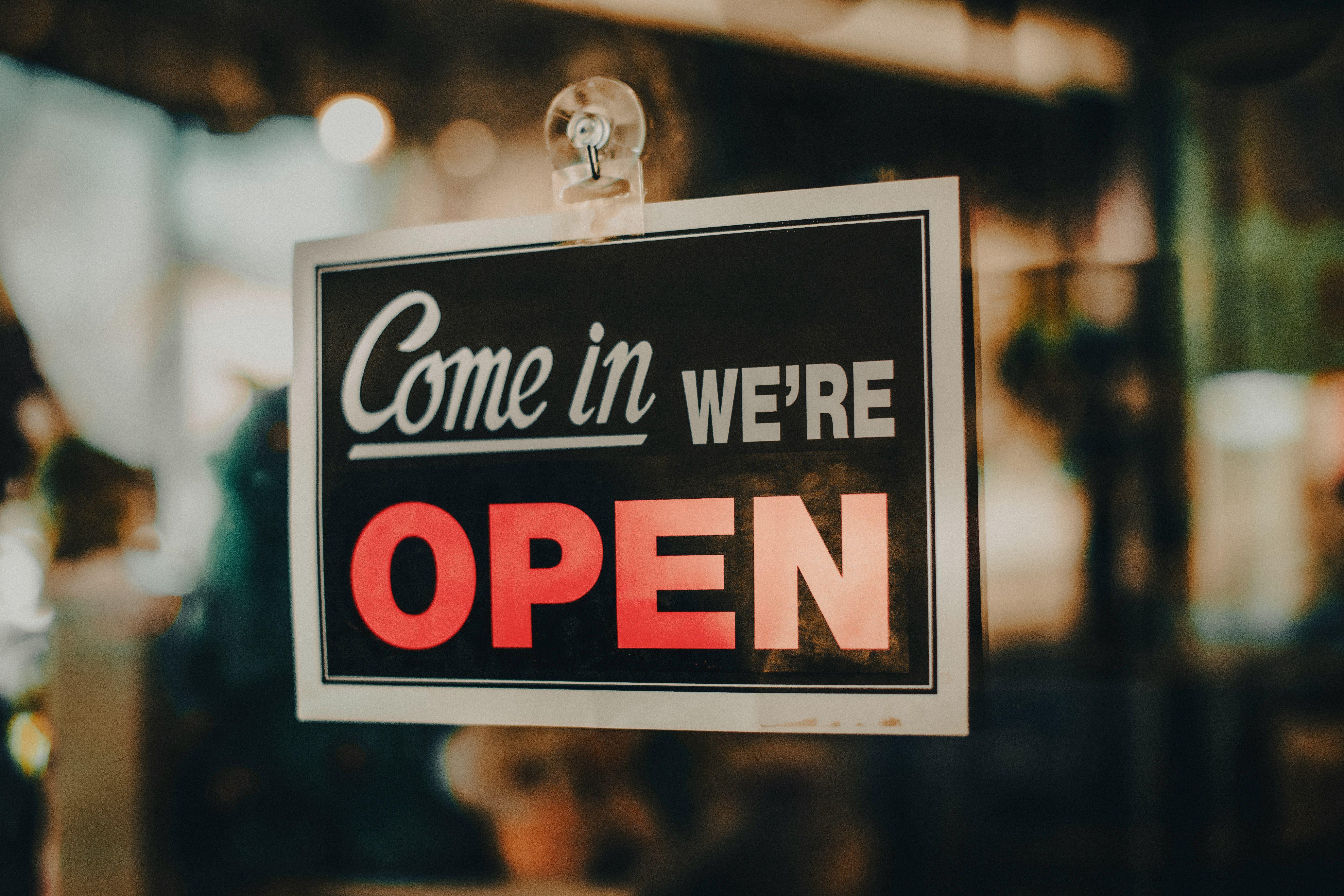 "Come in, we're open" sign hanging in a business window, representing a business owner's concerns about business division in an Illinois divorce