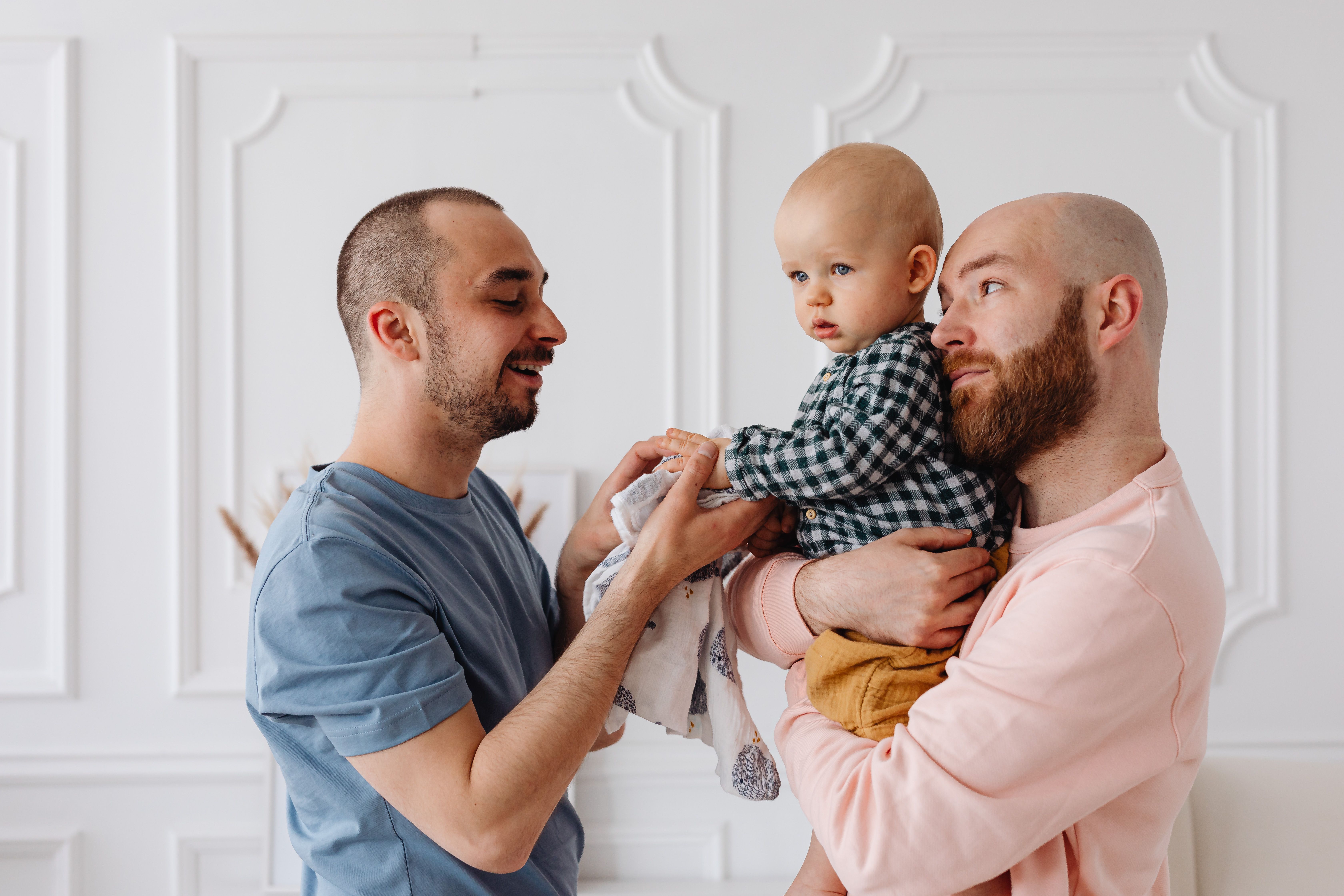 Two dads holding their baby together, representing LGBTQ+ family legal protections in Illinois.