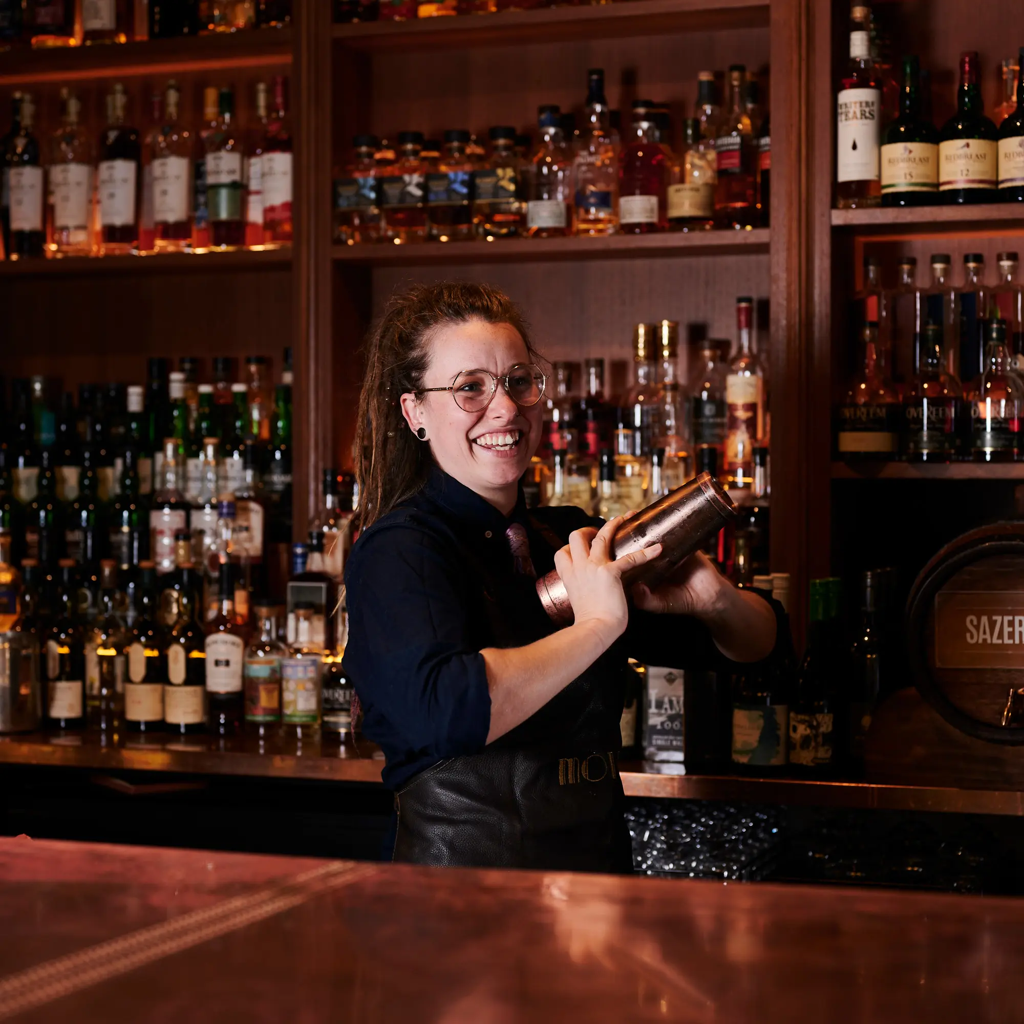 Female bartender smiling making cocktails at Molly