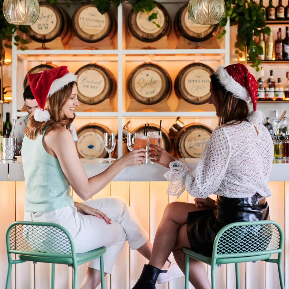 women smiling with santa hats and cocktails