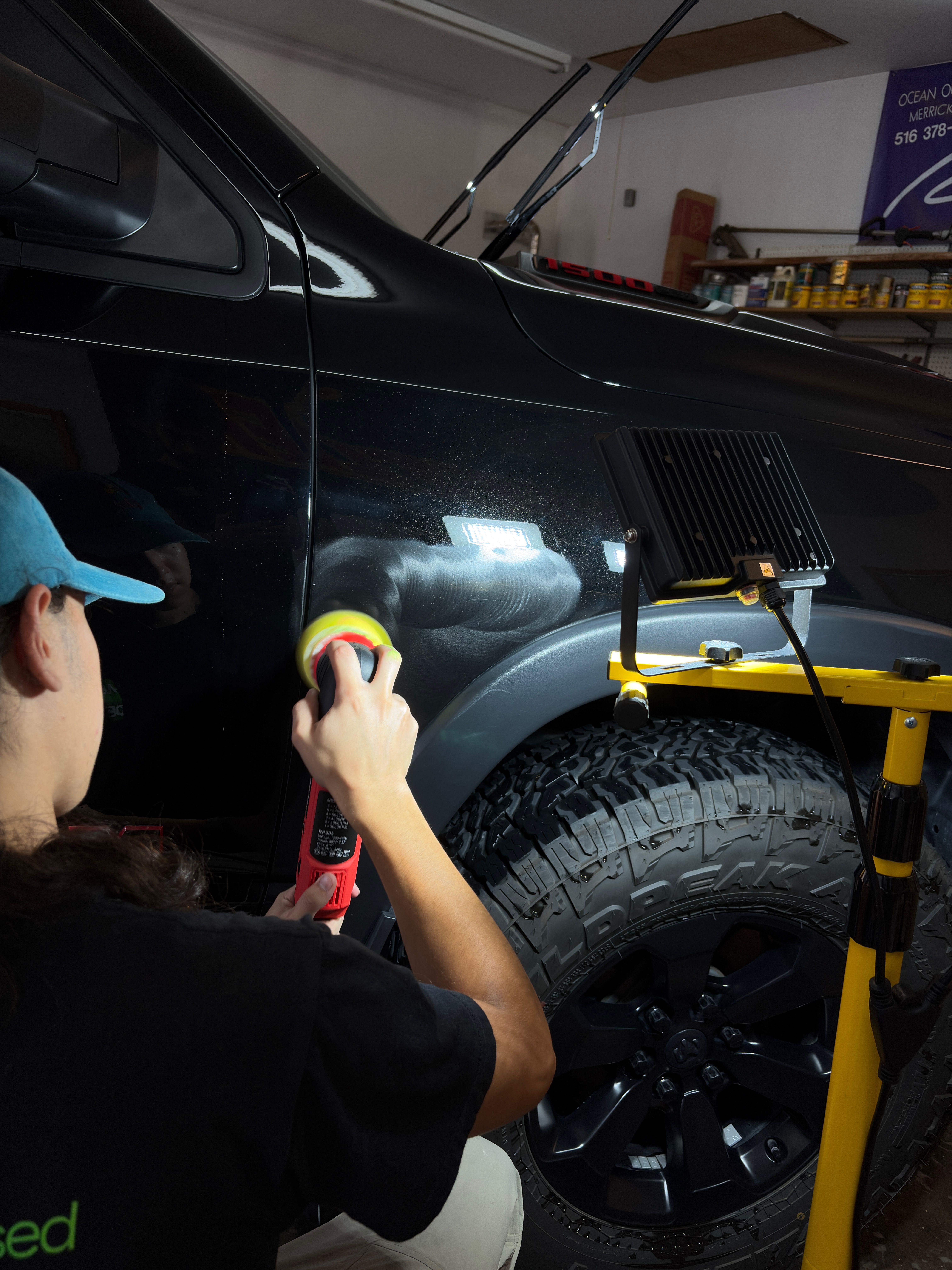 A M&L Detailing Technician polishing a black pickup truck on the passenger quarter panel.