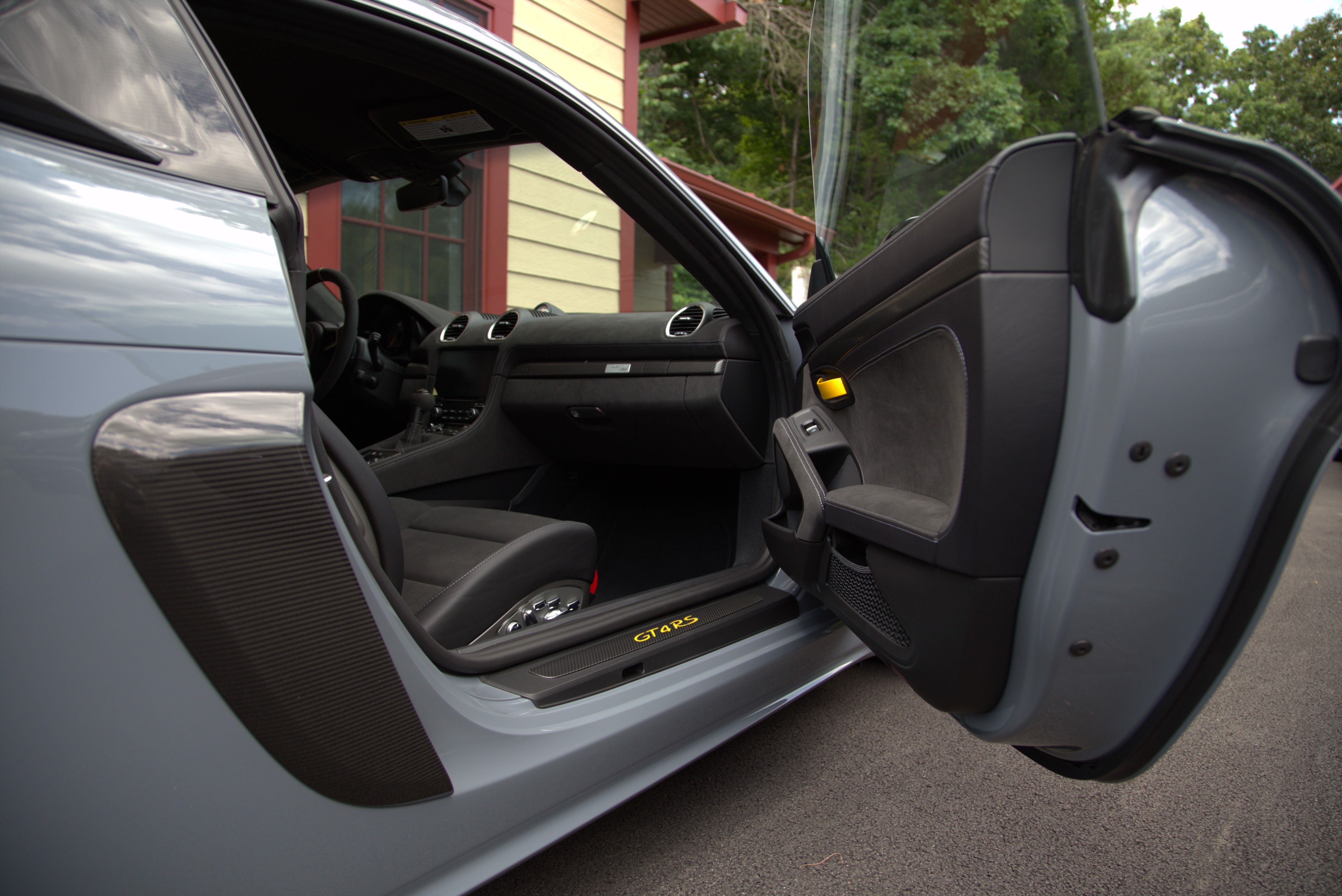 A image taken from the passenger's side of a Porsche GT4RS. The door jamb and some paint is visible, which is gleaming from being detailed. The dashboard and seat is also visible.