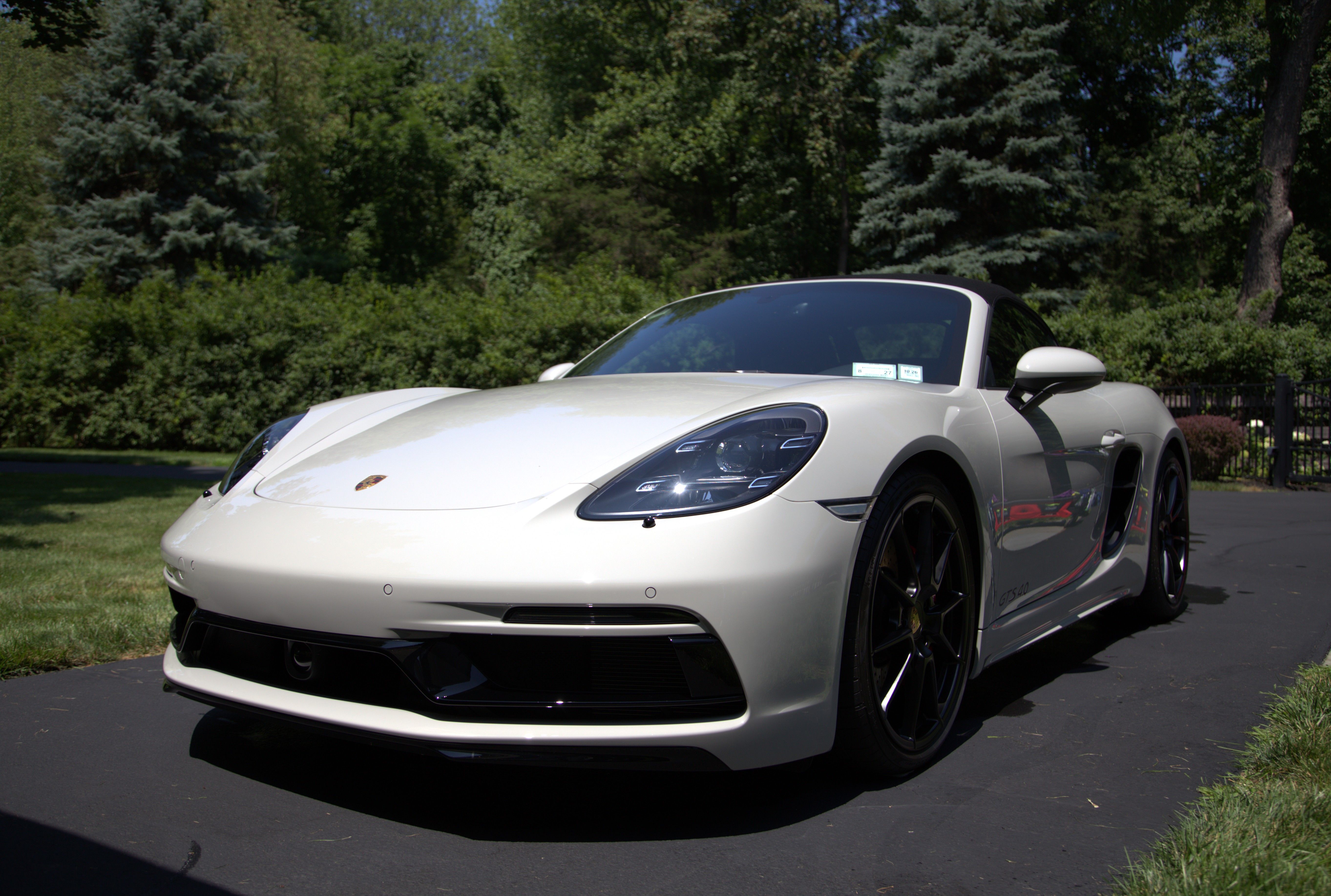 A side profile capture of a chalk-colored Porsche Boxster.