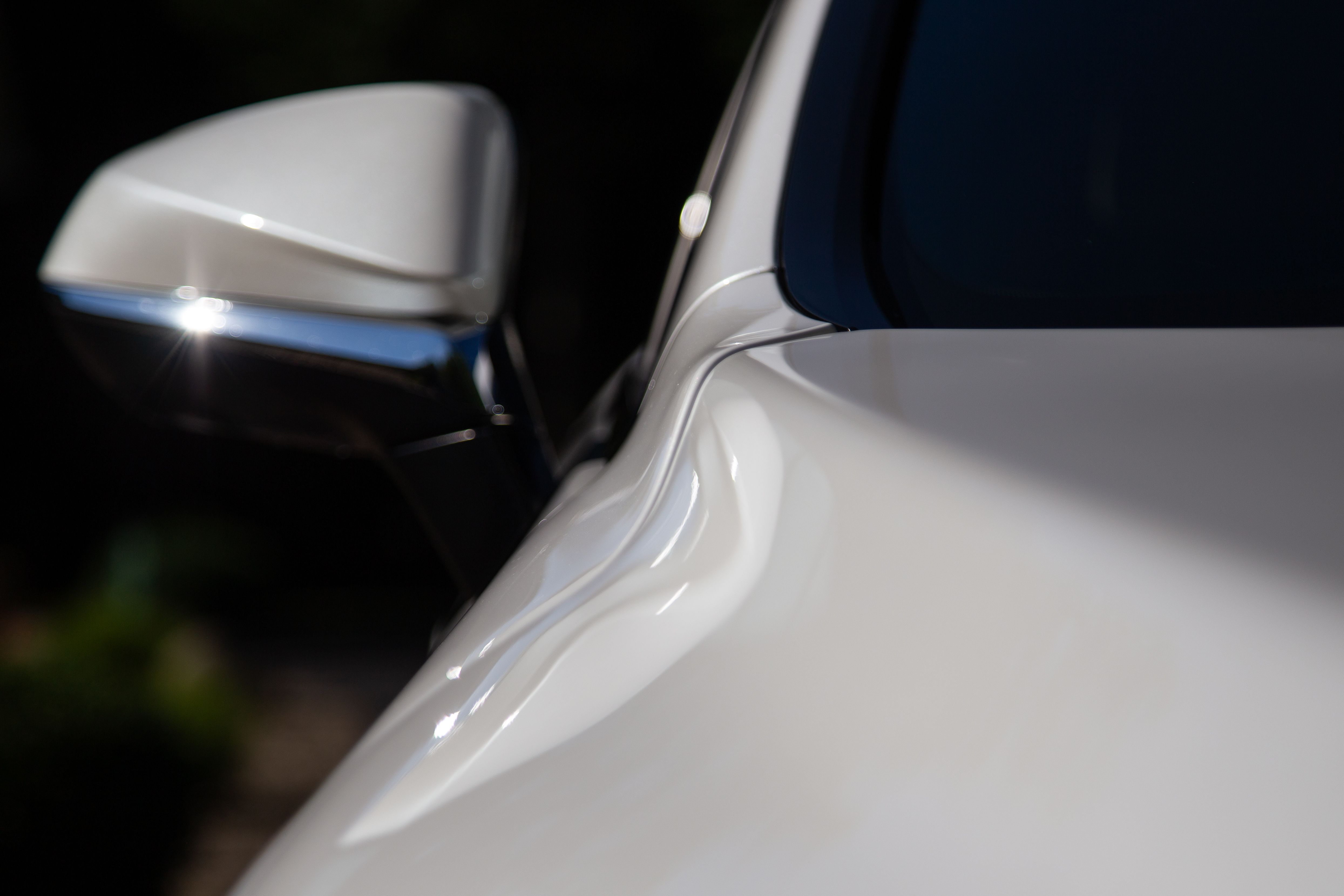 A photo of the hood and passenger side mirror on a Lexus RX350. The paint is pristine and sunlight is reflecting from the side mirror.