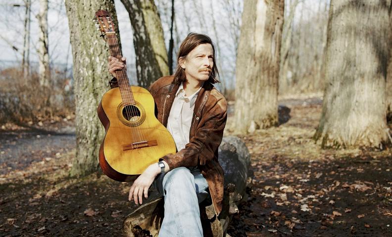 Tomi Leppänen kitaransa kanssa metsäisessä ympäristössä.