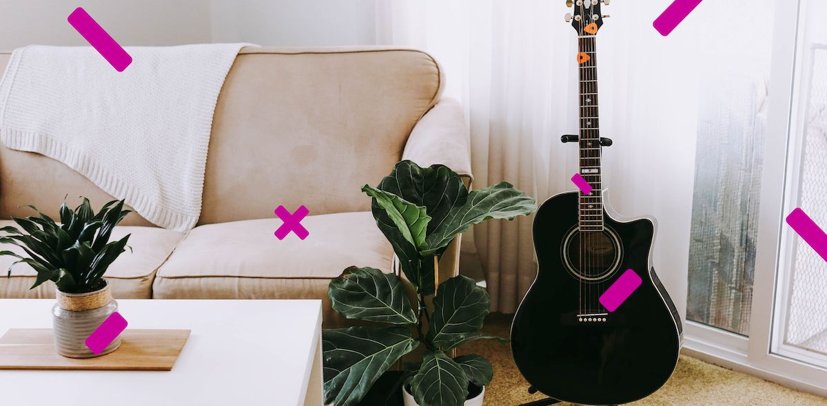 Kuva sohvalla, sohvapöydällä ja kitaralla sisustetusta huoneesta