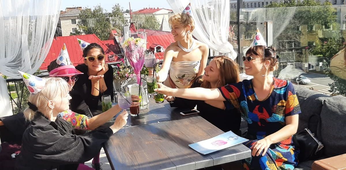 Kuvassa kuusi naista istumassa kahvilan pöydän ääressä