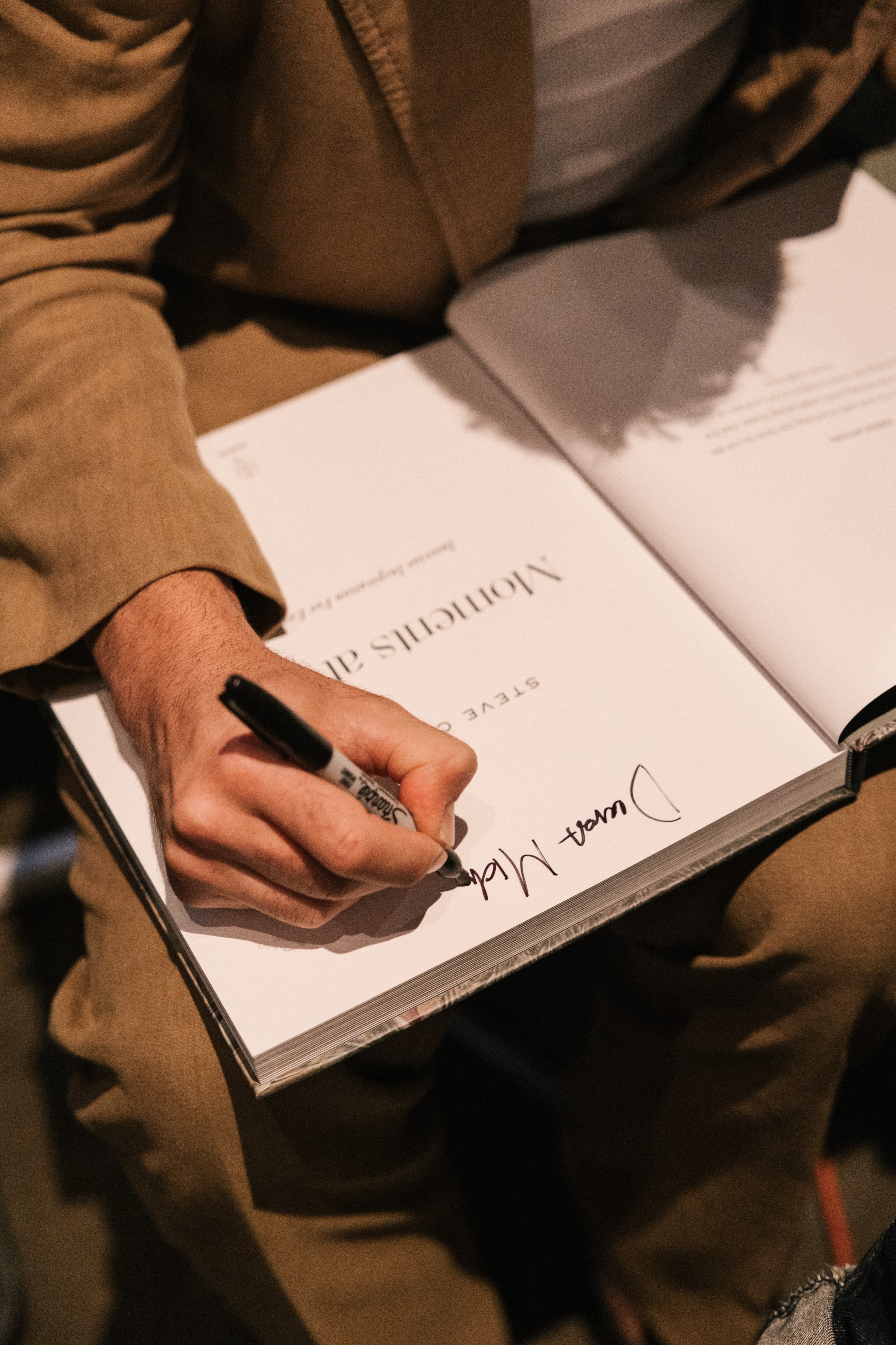 Author's hand signing a book