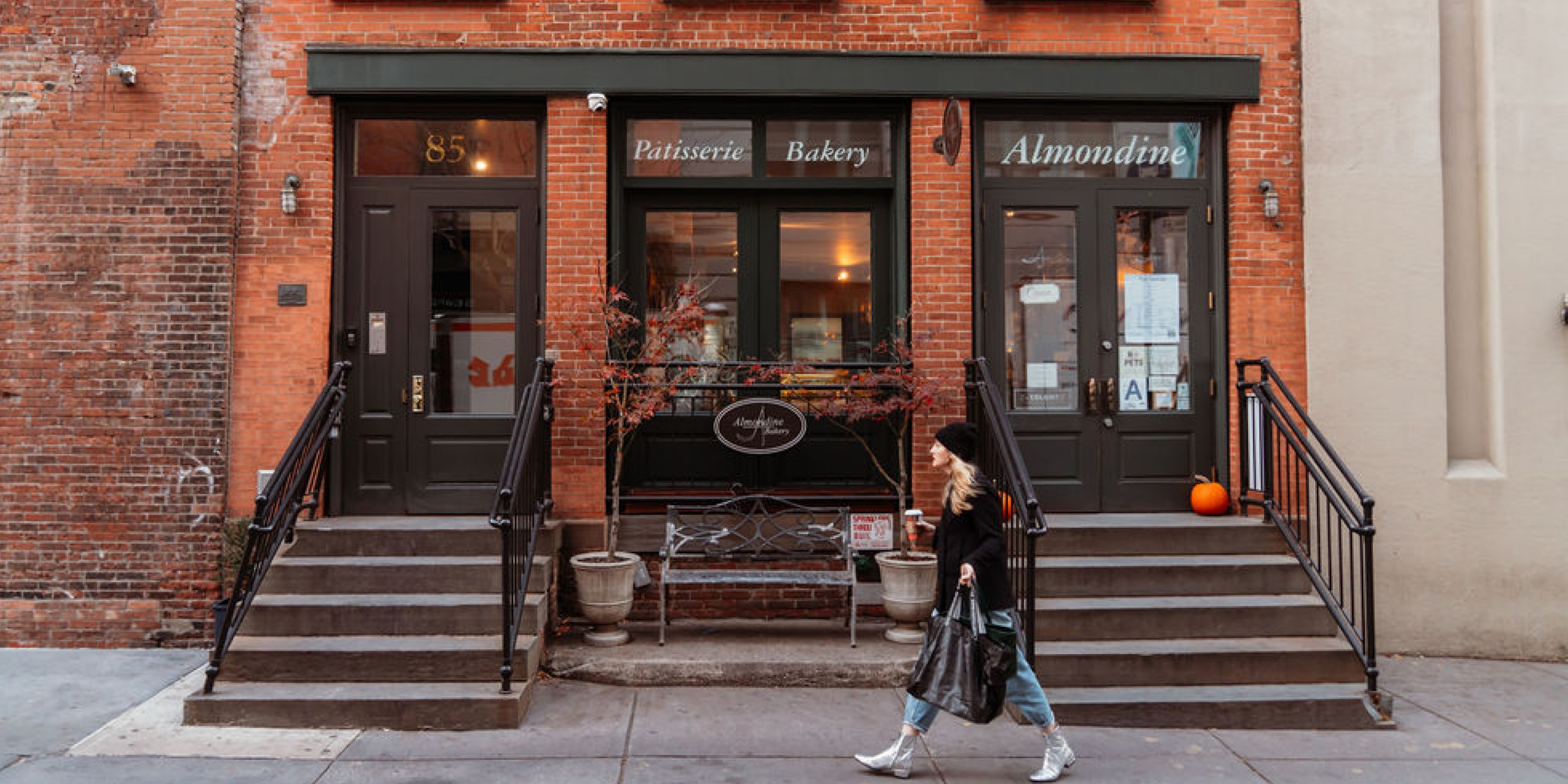 Urban coffee shop exterior with large windows, warm interior lighting, and a bicycle parked along the sidewalk.
