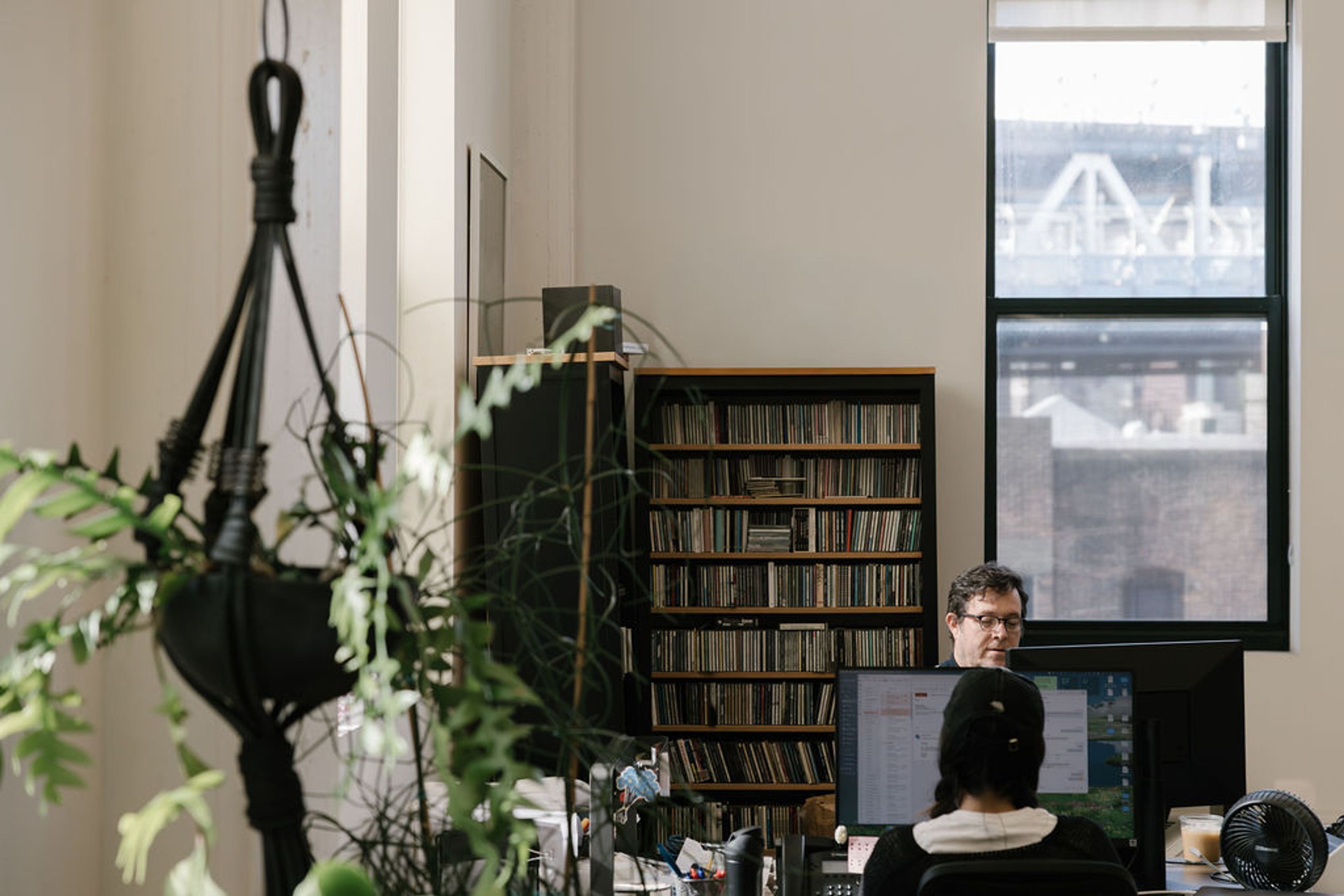 Man working at desk with window and bookcase in the background