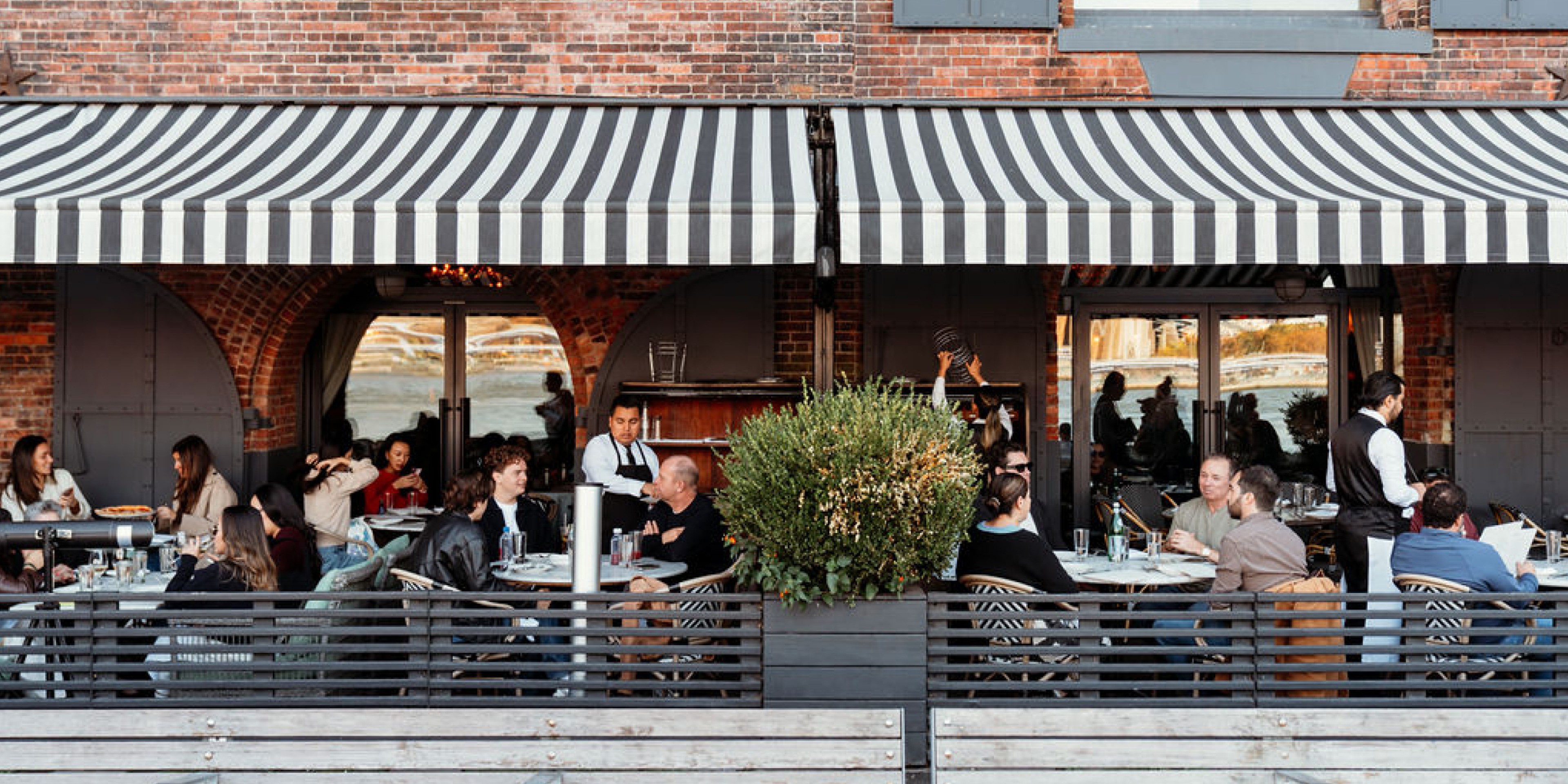 People eating on a patio with a striped awning above them