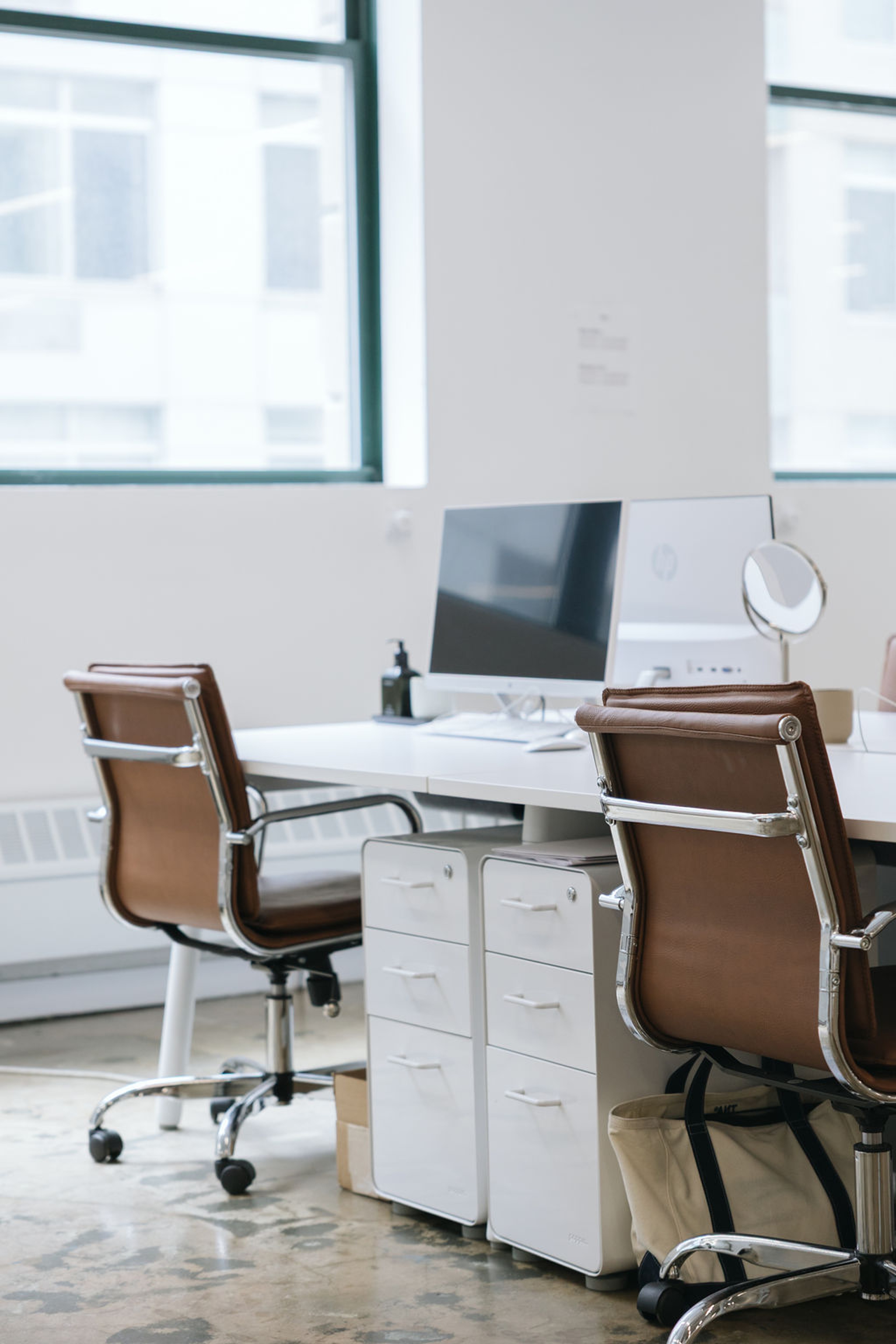 a sunny desk with a computer monitor and brown leather chair