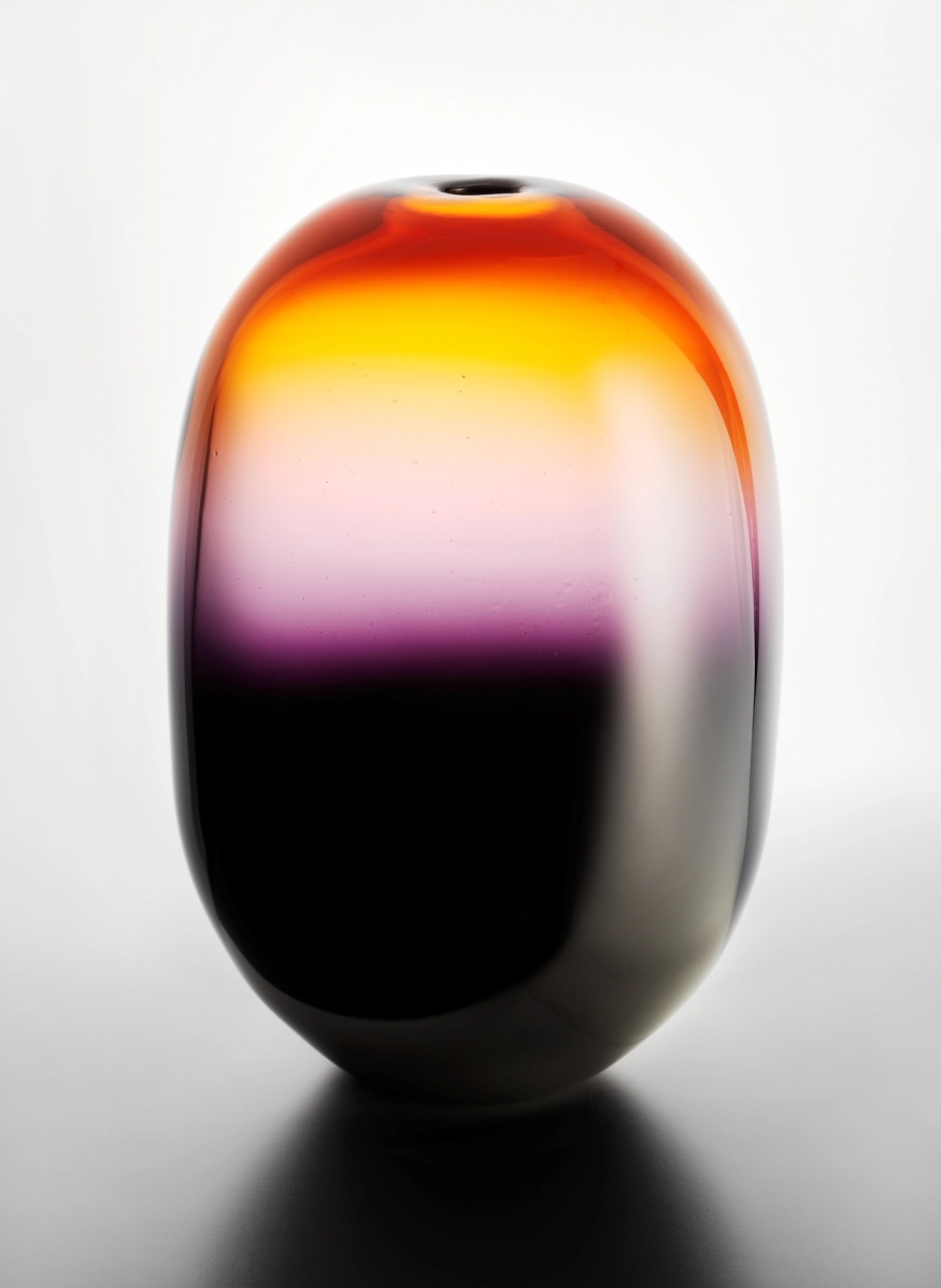Glassvase i farger som går gradert fra svart til oransje/gult.
