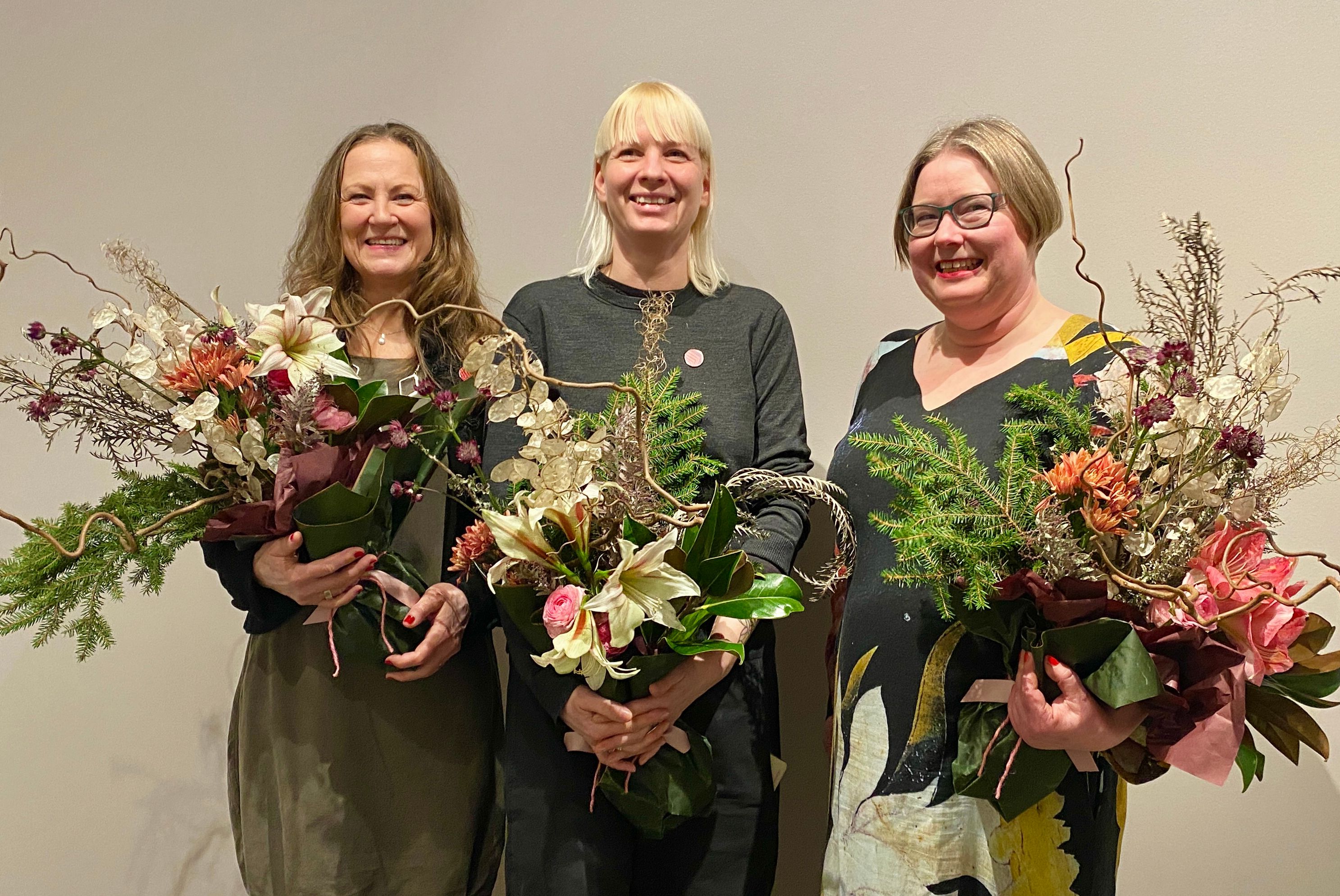 Tre glade prisvinnere med store buketter