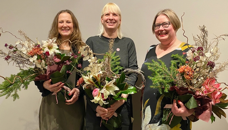 Tre glade prisvinnere med store buketter