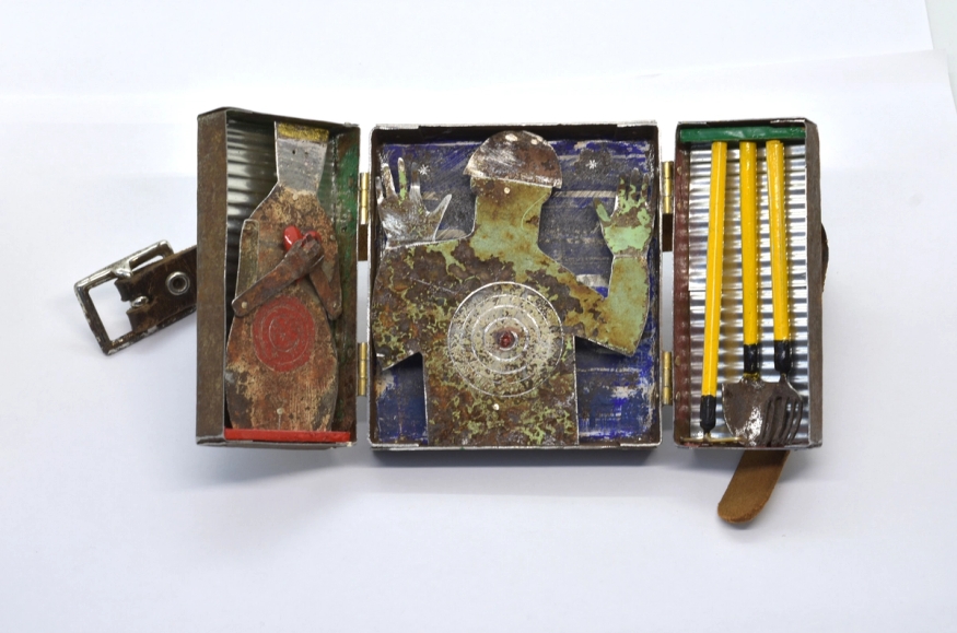 Bildet viser en metallkoffert som innholder tre kunstverk i metall