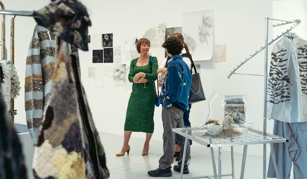 Tre mennesker står i et hvitt gallerirom, omringet av kunstverk