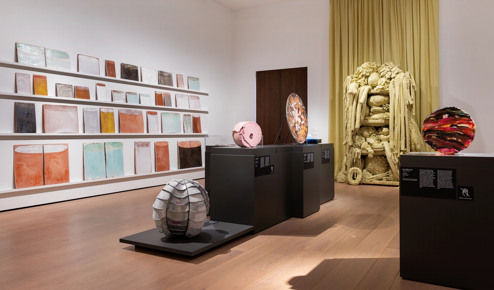 Installasjonsfoto fra utstilling som viser arbeider i tekstil, keramikk, glass og metall.