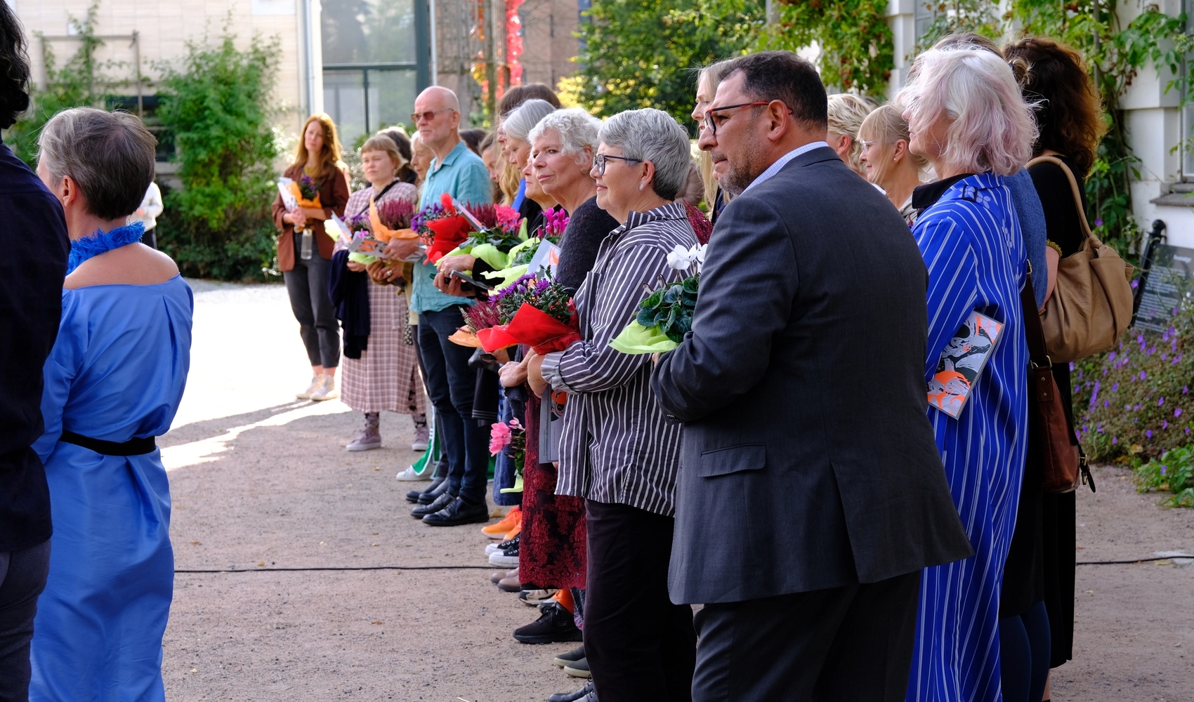 Mange kunstnere står foran en museumsbygning ved åpningen av deres utstilling