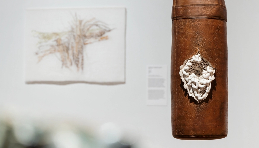 Installasjonsfoto med et tekstilverk og en boksepute-skulptur