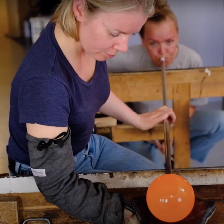 Videostillbilde av Kristiansen og Paalgard som samarbeider med Glassblåsing