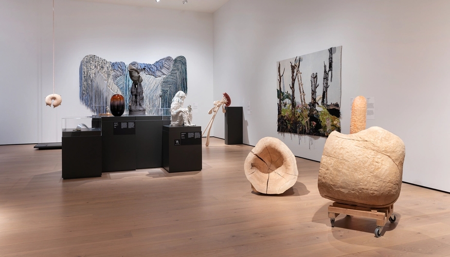 Installasjonsfoto som viser tekstilarbeider på en vegg og skulpturer ute i rommet