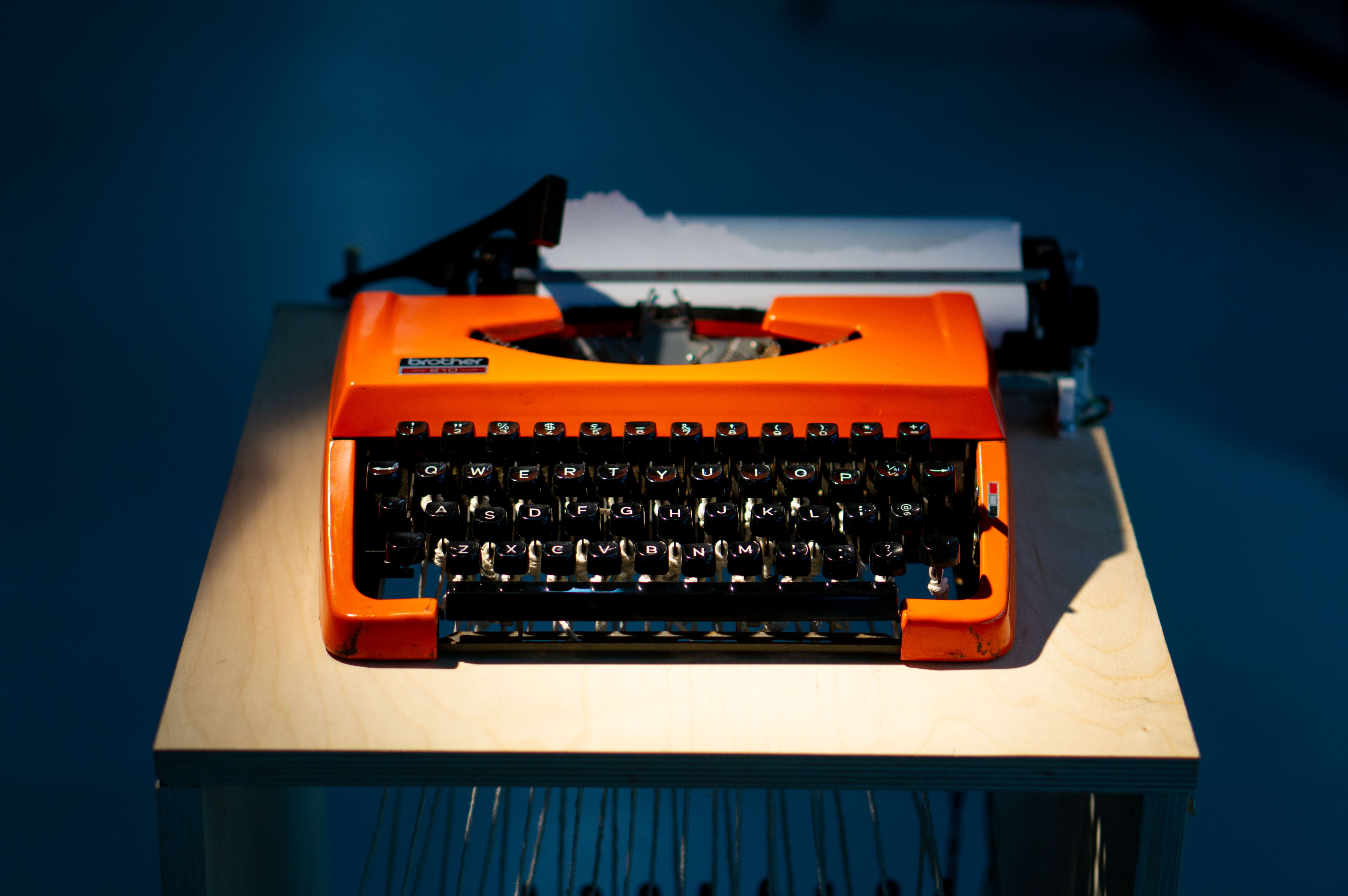 orange typewriter viewed from the front, dramatically lit