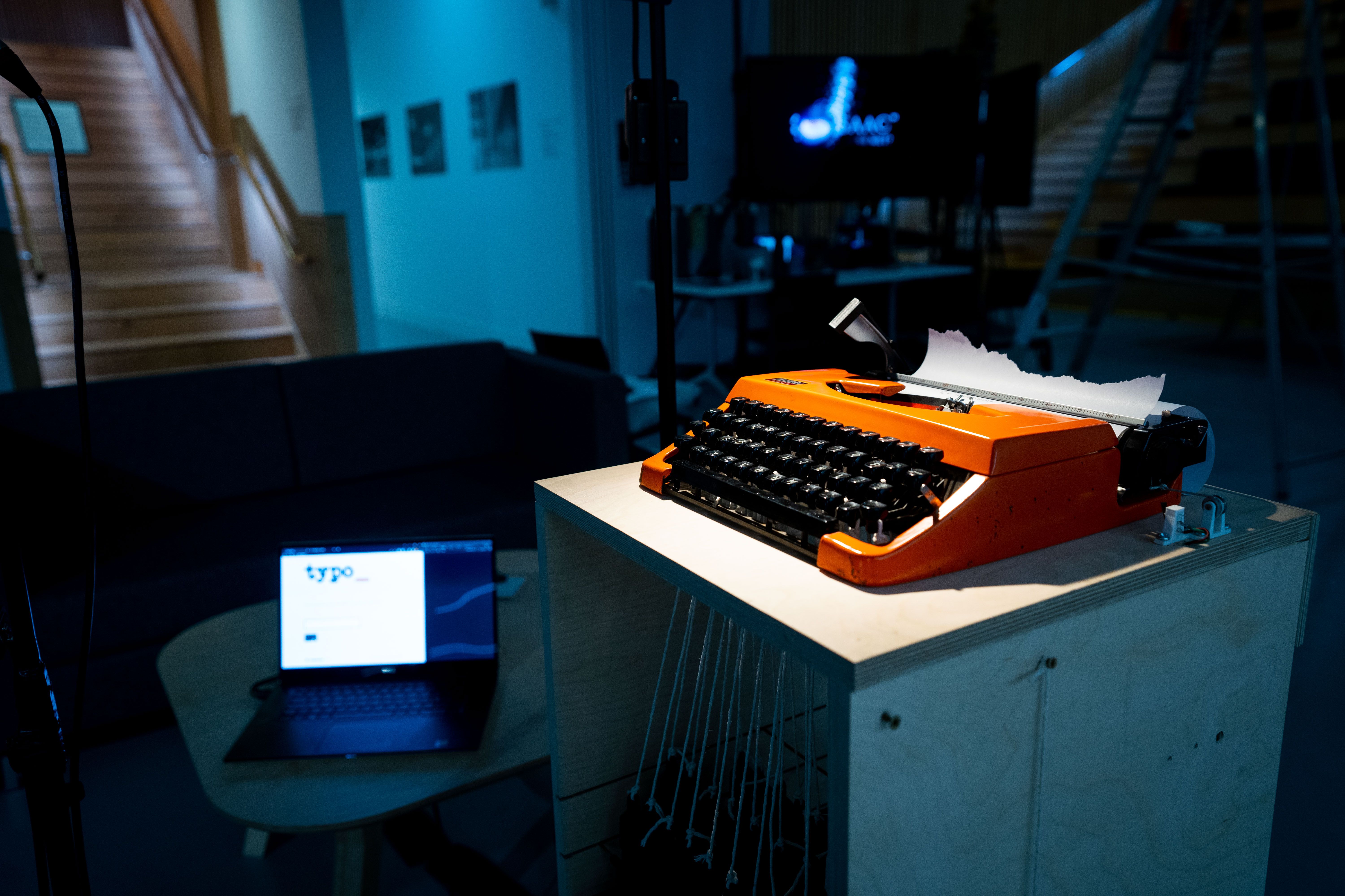 orange typewriter in the forgeround with a laptop running software titled "typo"in the background