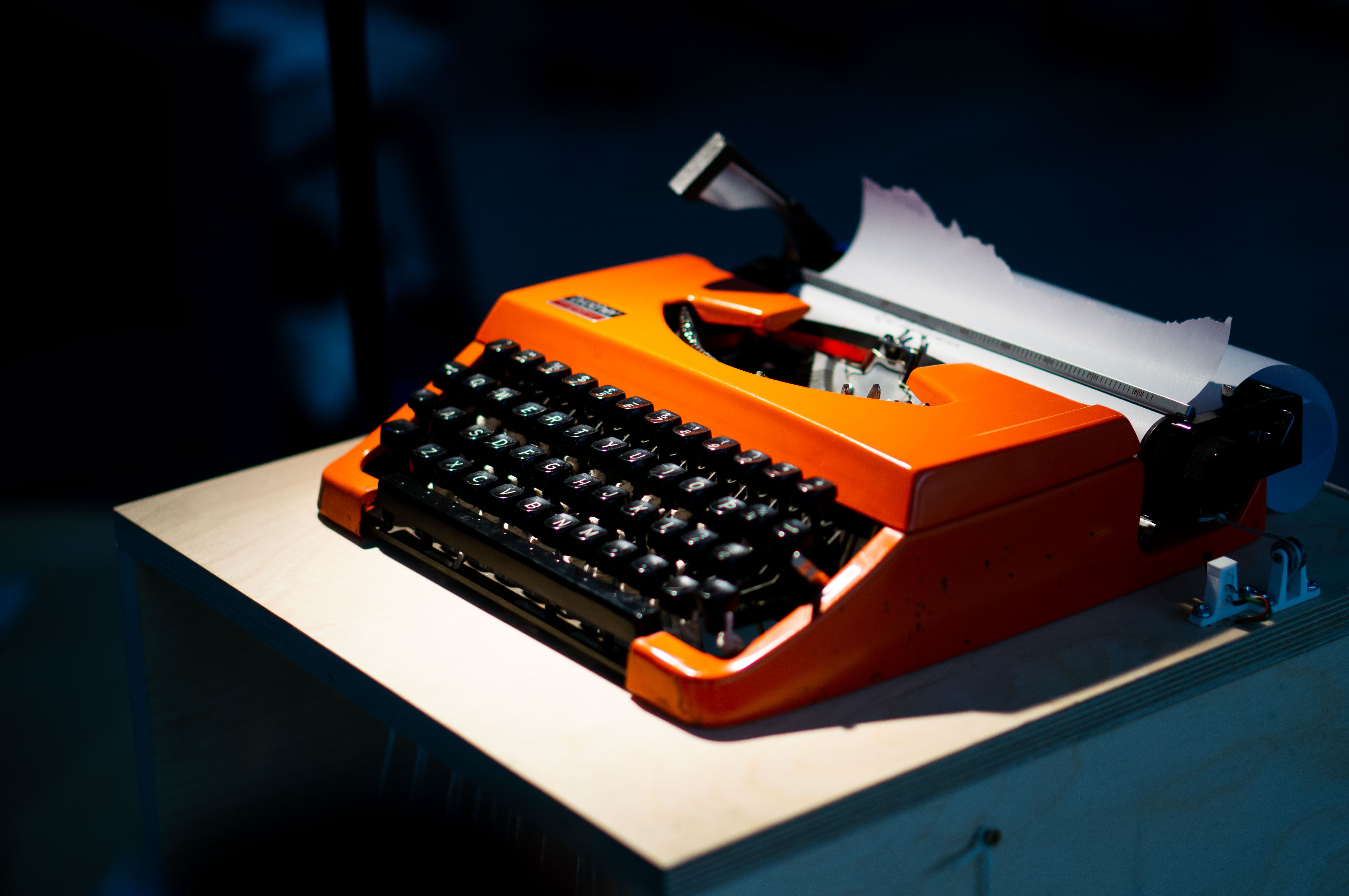 close up view of orange typewriter, dramatically lit