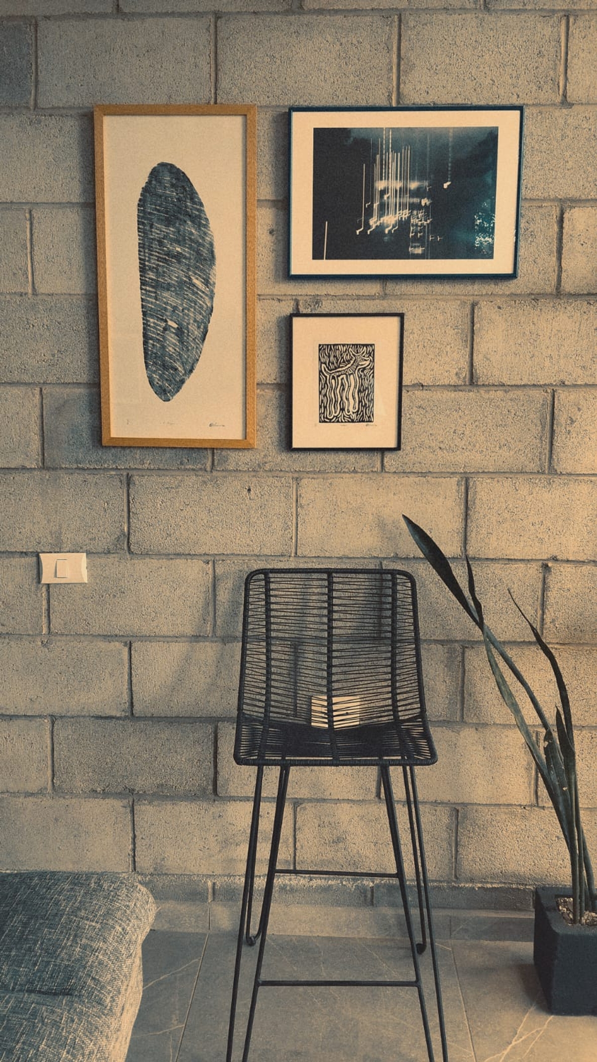 Espacio creativo de Estudio Ser con obras enmarcadas en pared de bloques y silla de diseño