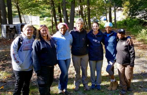 Seven women in the forest with arms around each other