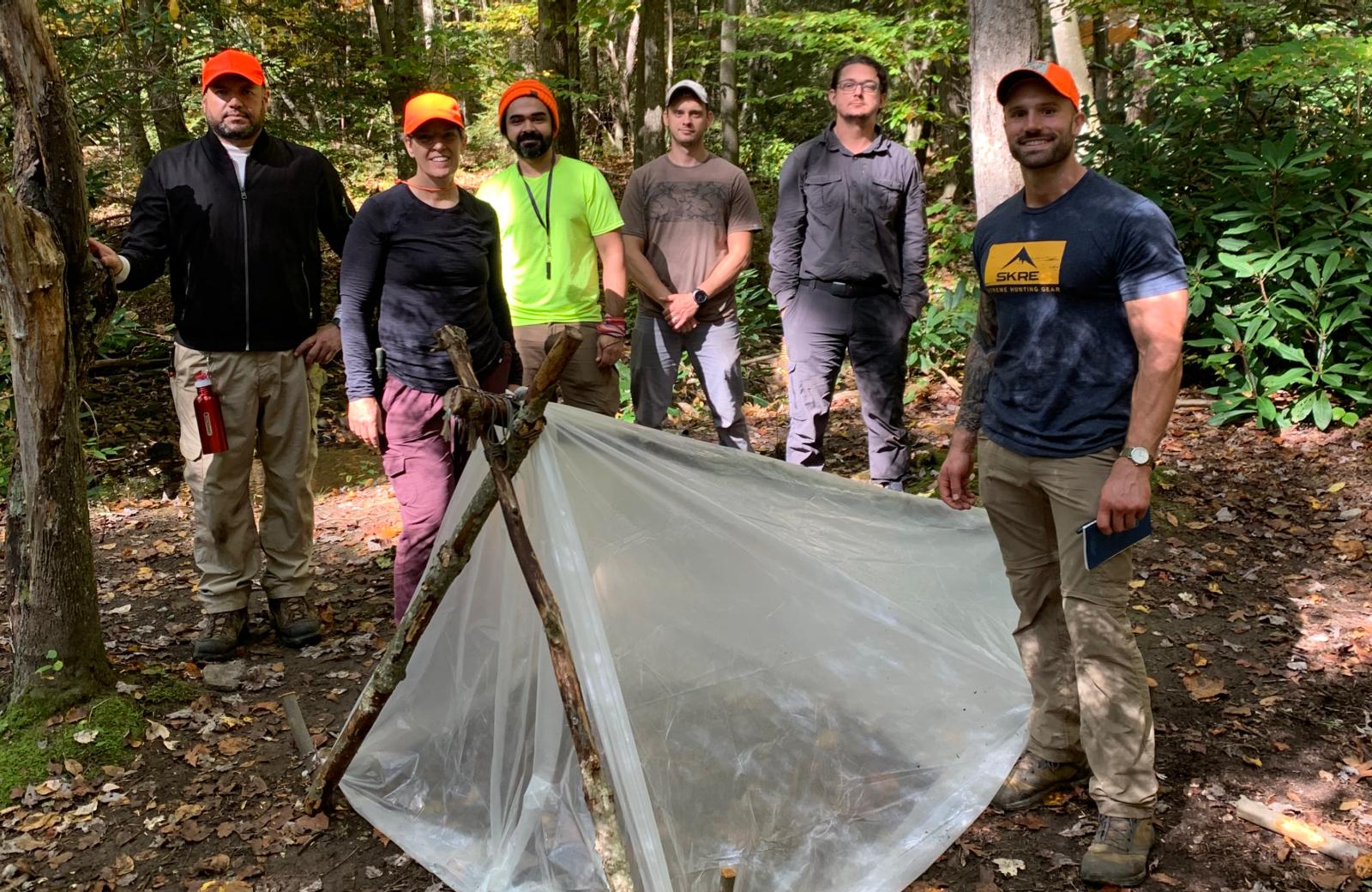 Group in front of hand made tent in forest