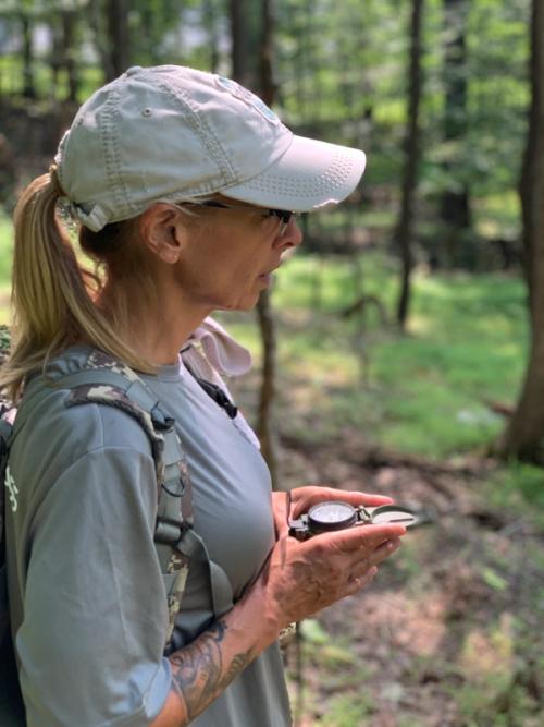 Woman with hat, pony tail, and compas in outdoors