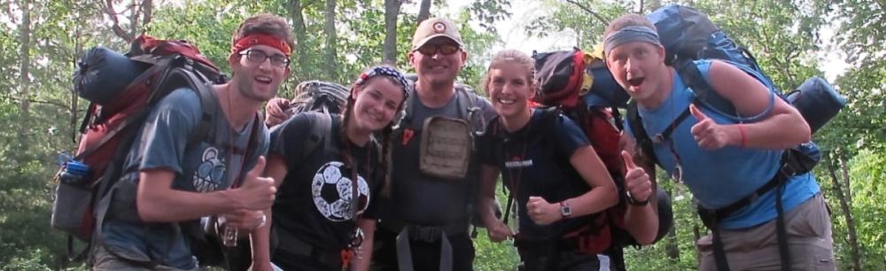 Group of wilderness survivalists posing for camera in forest