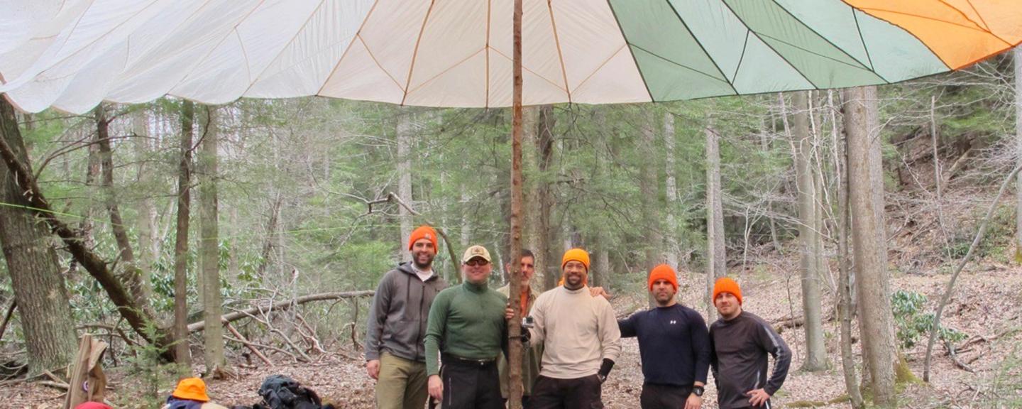 Group standing proudly under a parachute