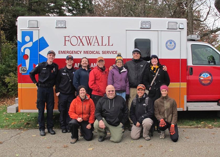 An ambulance with a group of people standing along side of it.