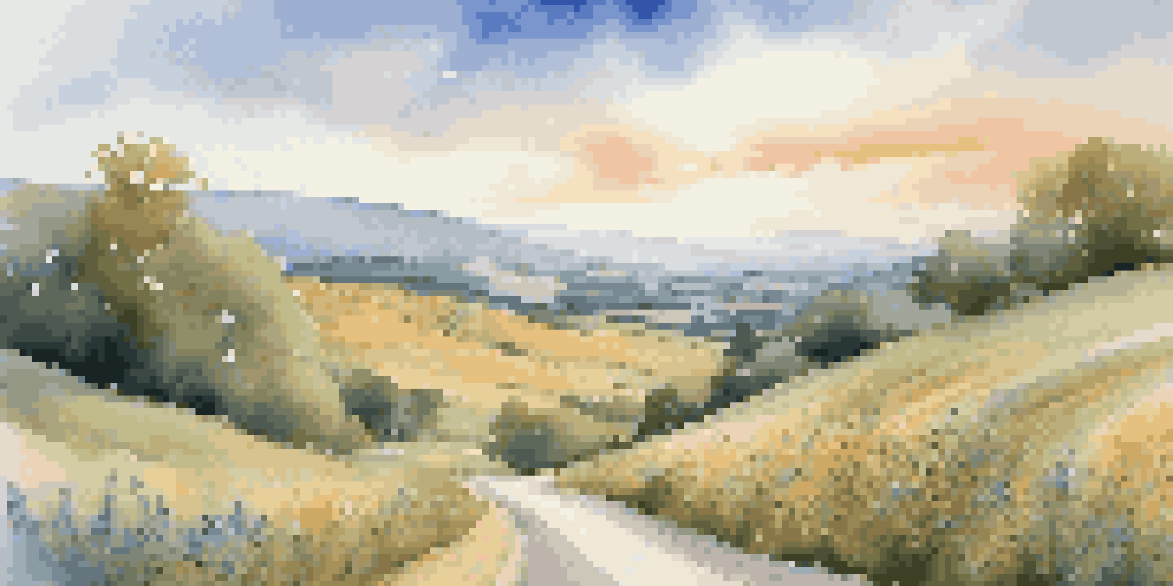A winding road through a beautiful countryside with rolling hills and colorful wildflowers under a bright blue sky.