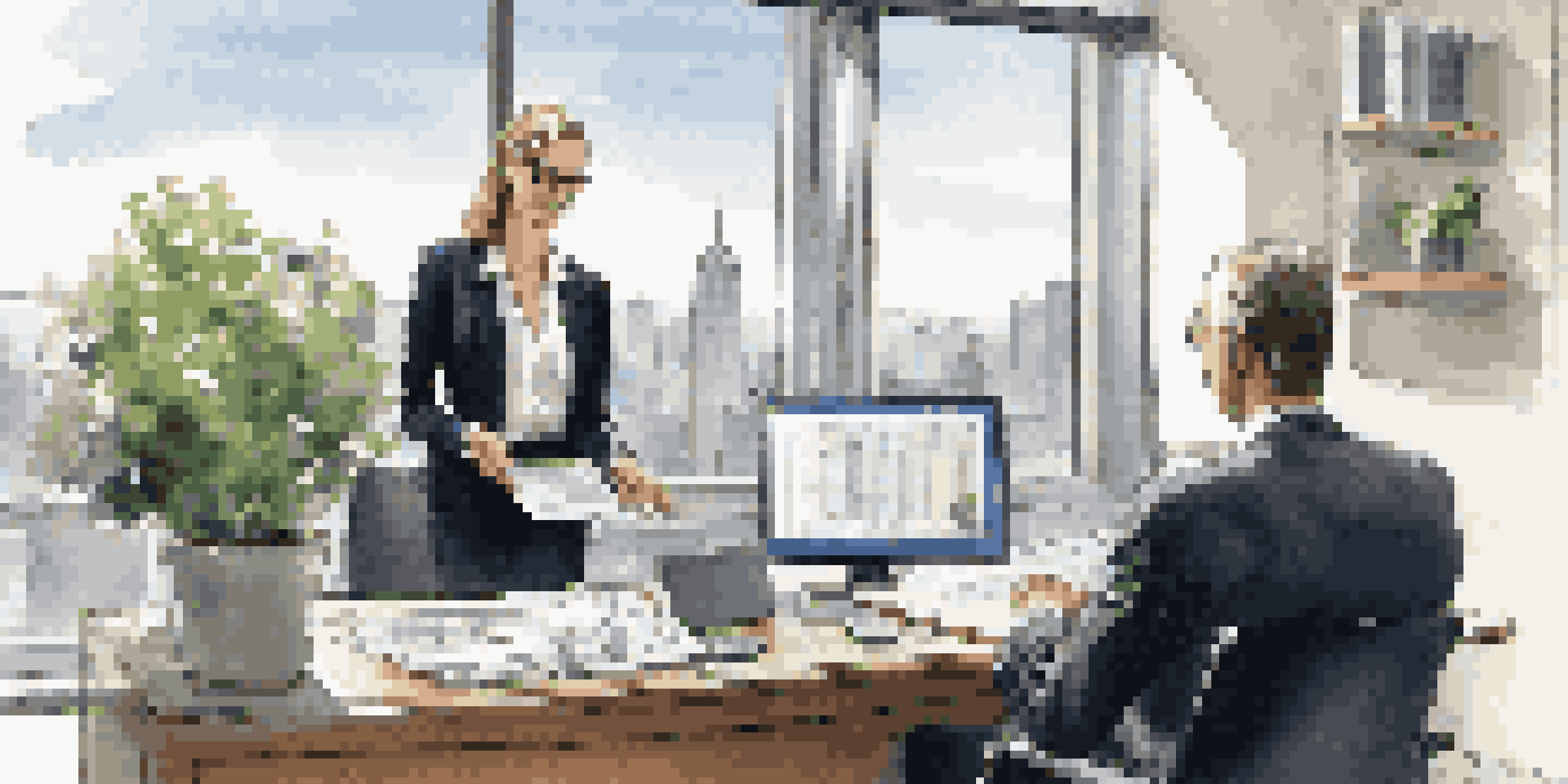 A financial advisor in a modern office, interacting with a client over a laptop, with a city skyline view in the background.