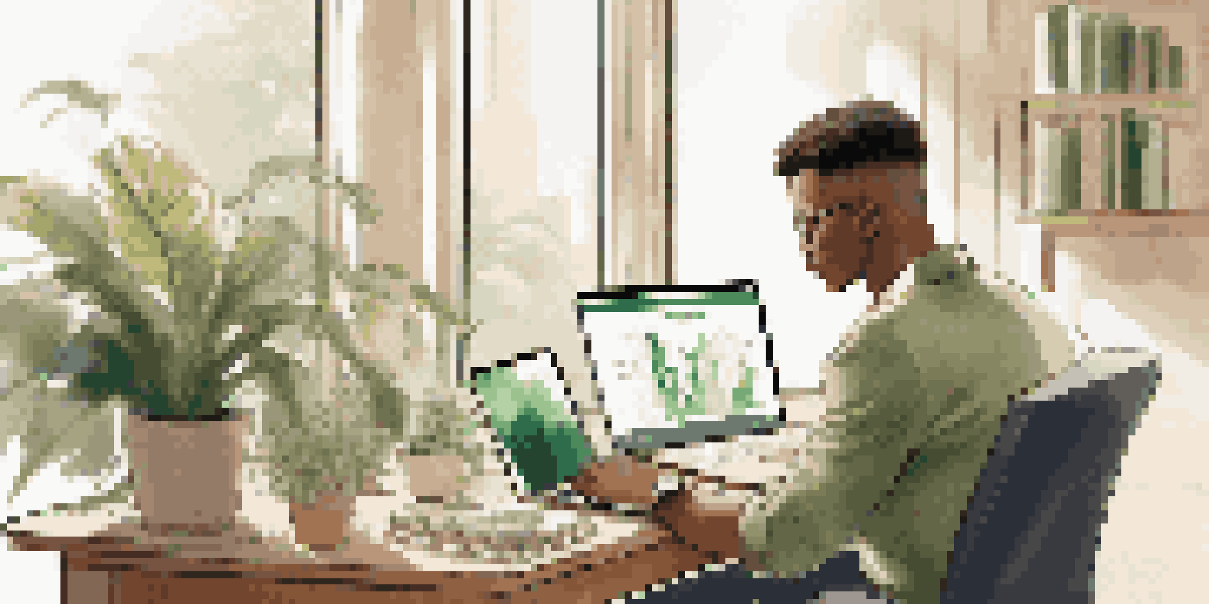 A young investor focused on their laptop, surrounded by plants and investment books in a well-lit room.