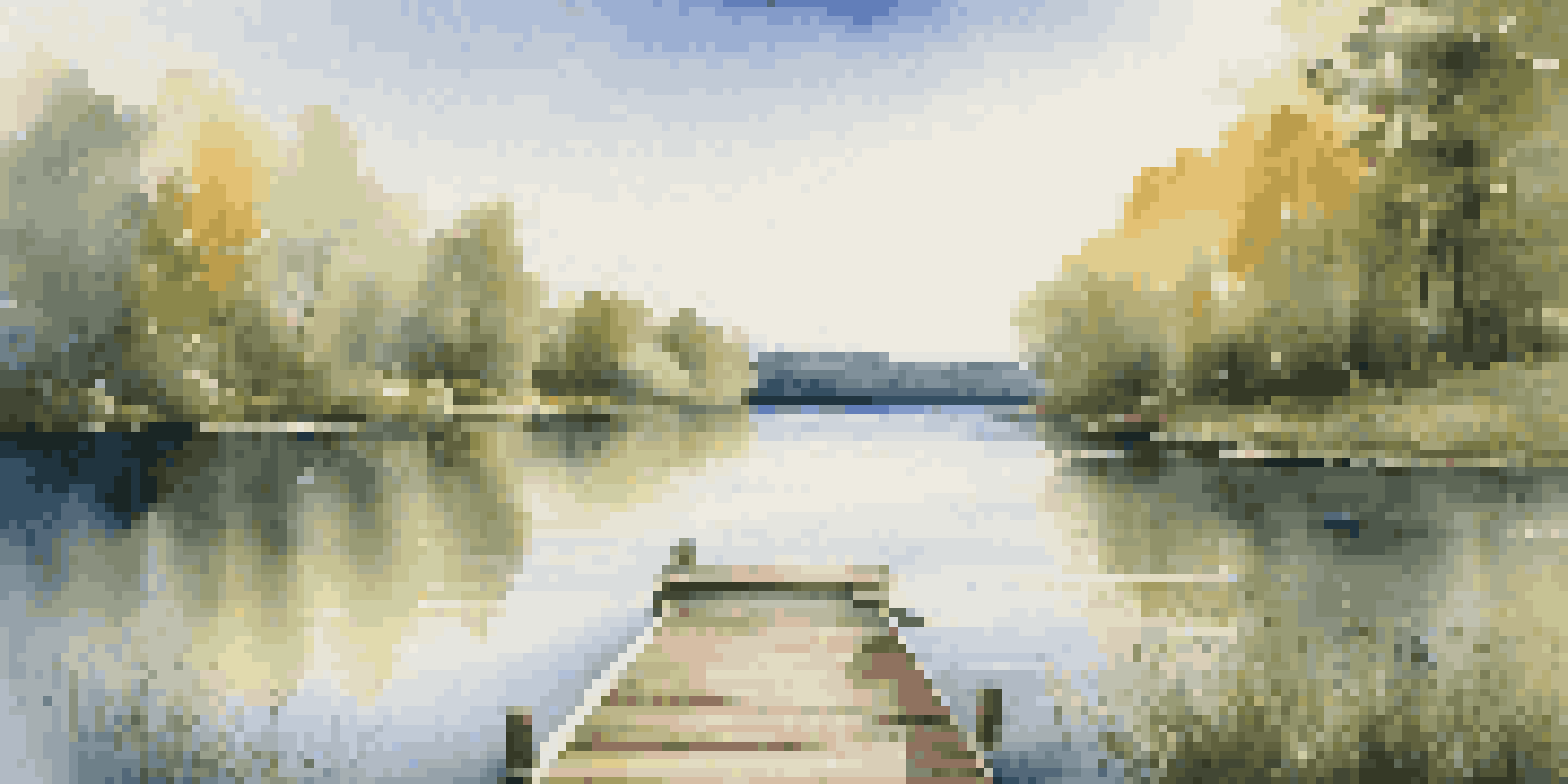 A peaceful lake scene with green forests and a wooden dock, under a clear blue sky.