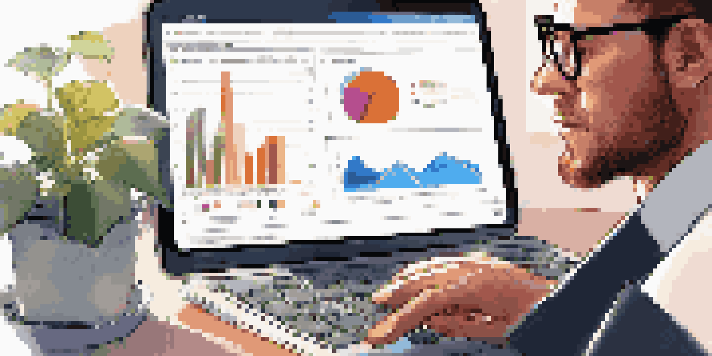 A financial analyst analyzing data on a laptop with colorful charts, in a modern workspace with a plant and coffee.
