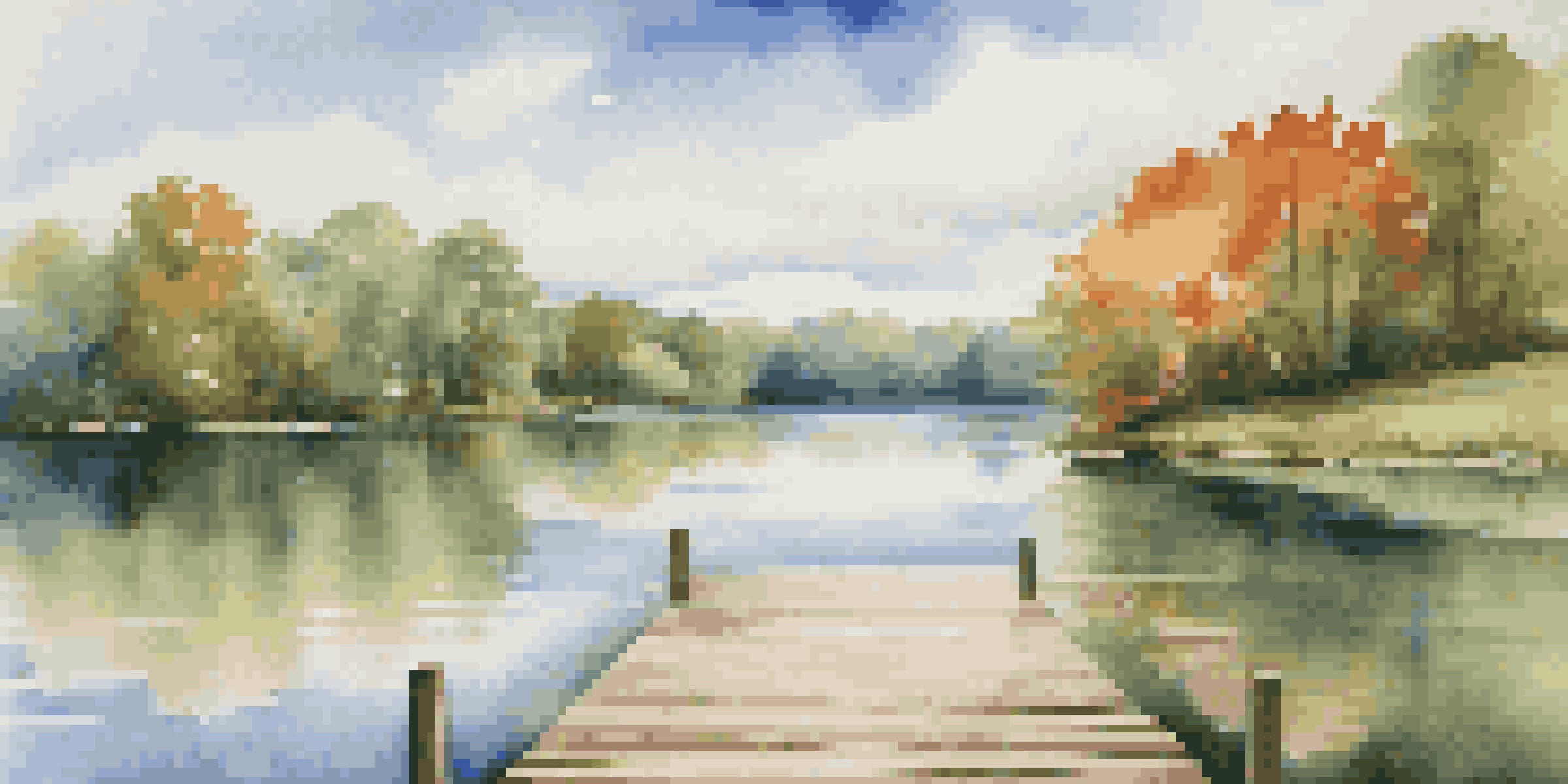 A calm lake surrounded by green trees with a blue sky and a wooden dock extending into the water.