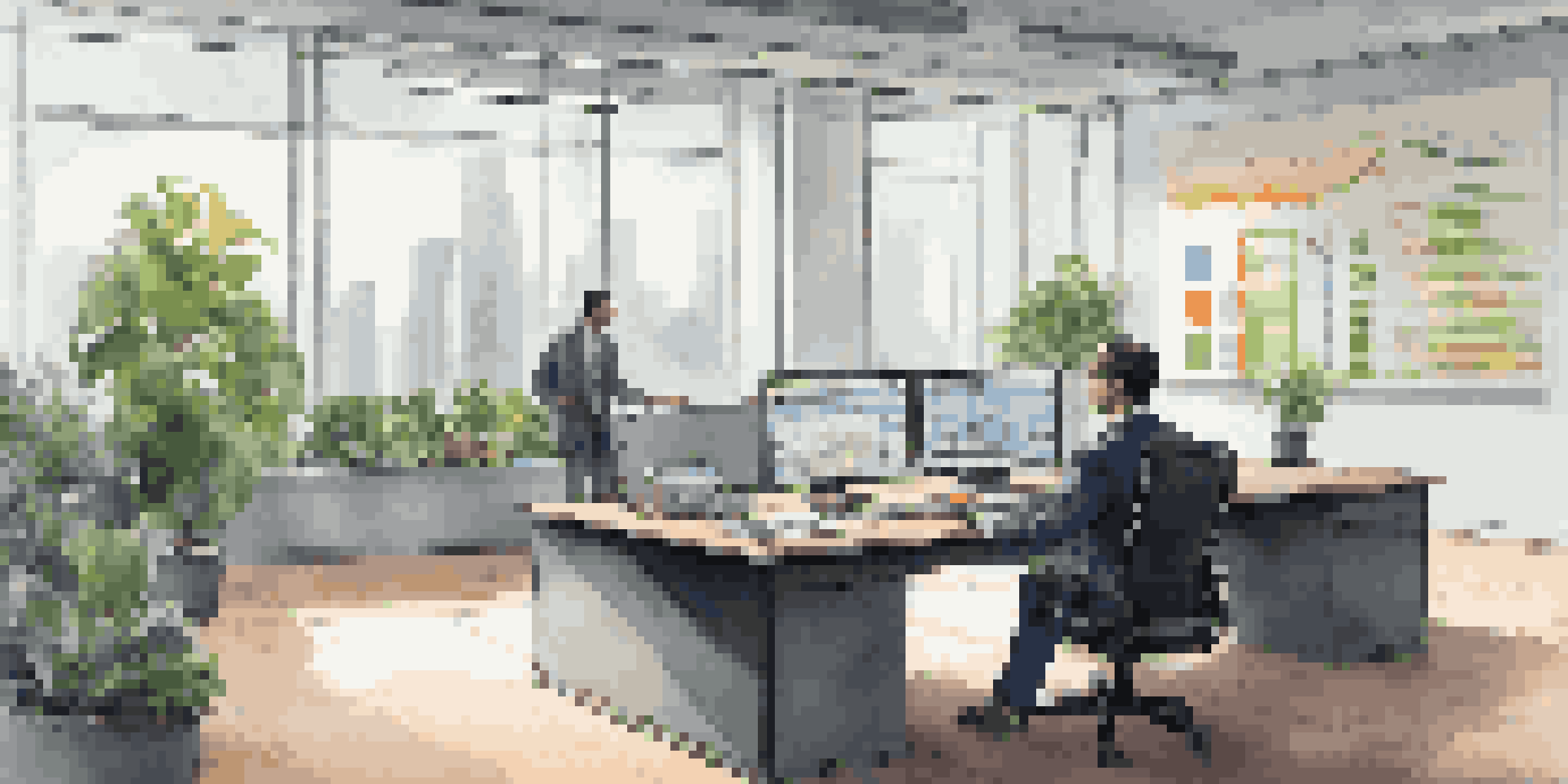 A wealth manager in an office analyzing financial models on a computer screen, surrounded by plants and charts.