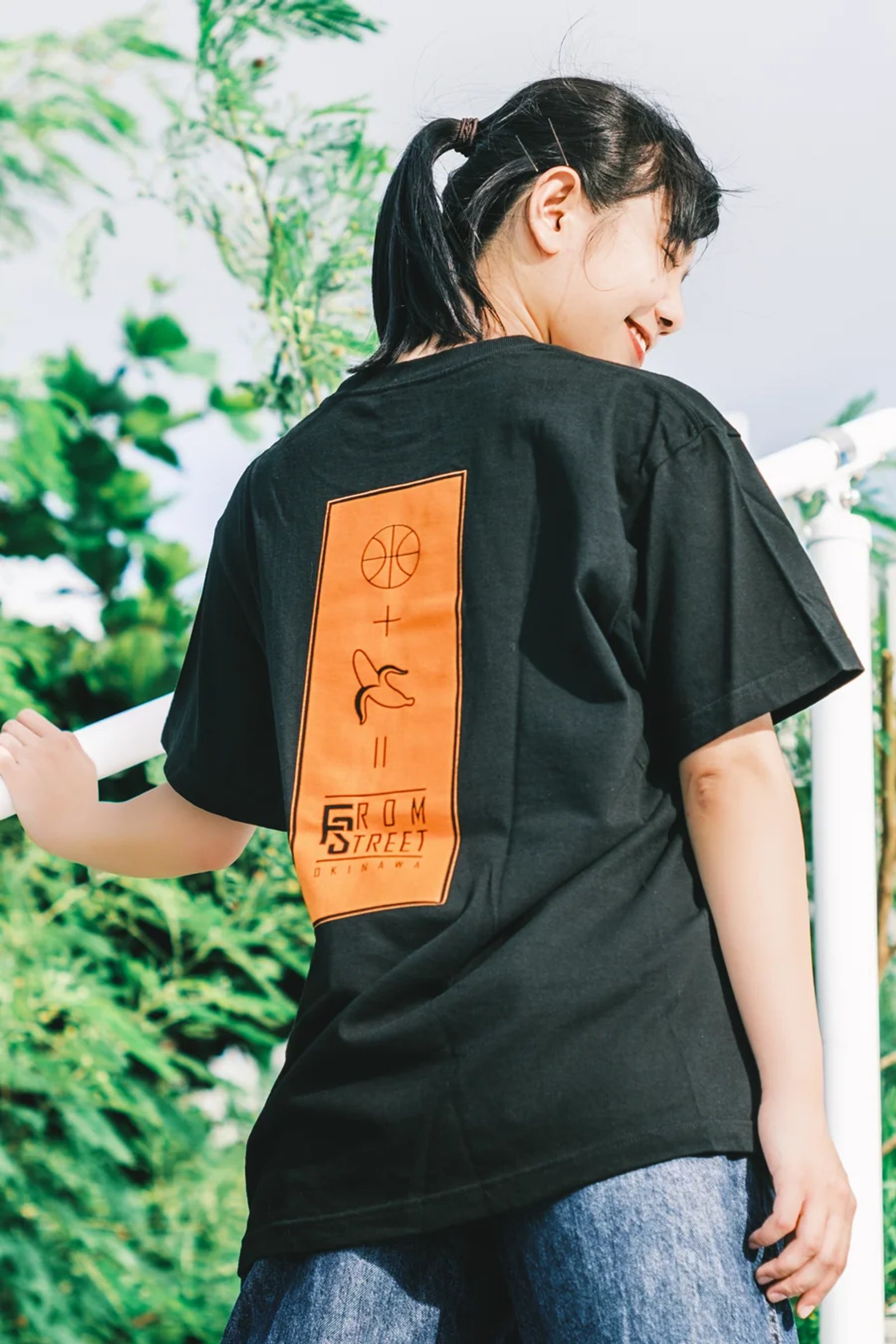 オレンジ色のバスケットボールとバナナのバックプリントが入った黒いFrom StreetのTシャツの着用写真