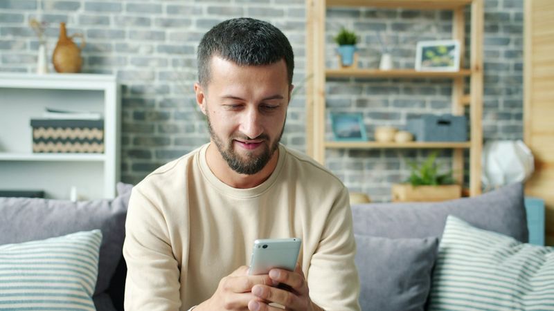 A man on a couch texting on his phone