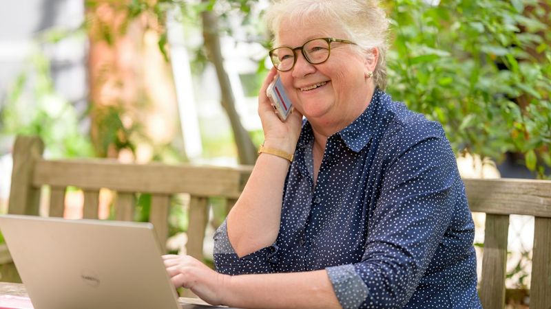 A woman on a phone call at a table with a laptop